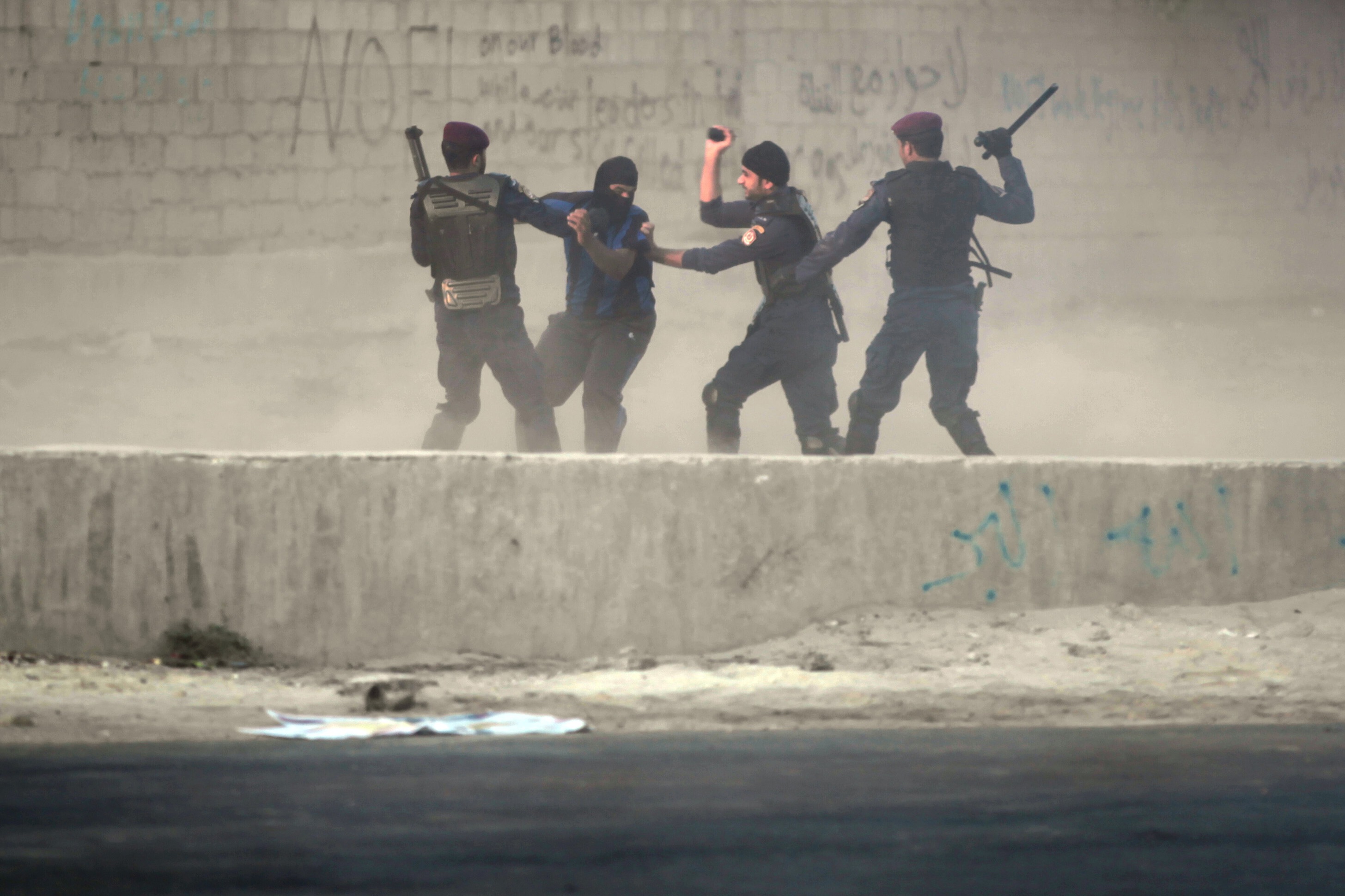 Riot police catch a Bahraini anti-government protester in the village of Shakhura, Bahrain, on 14 August 2013