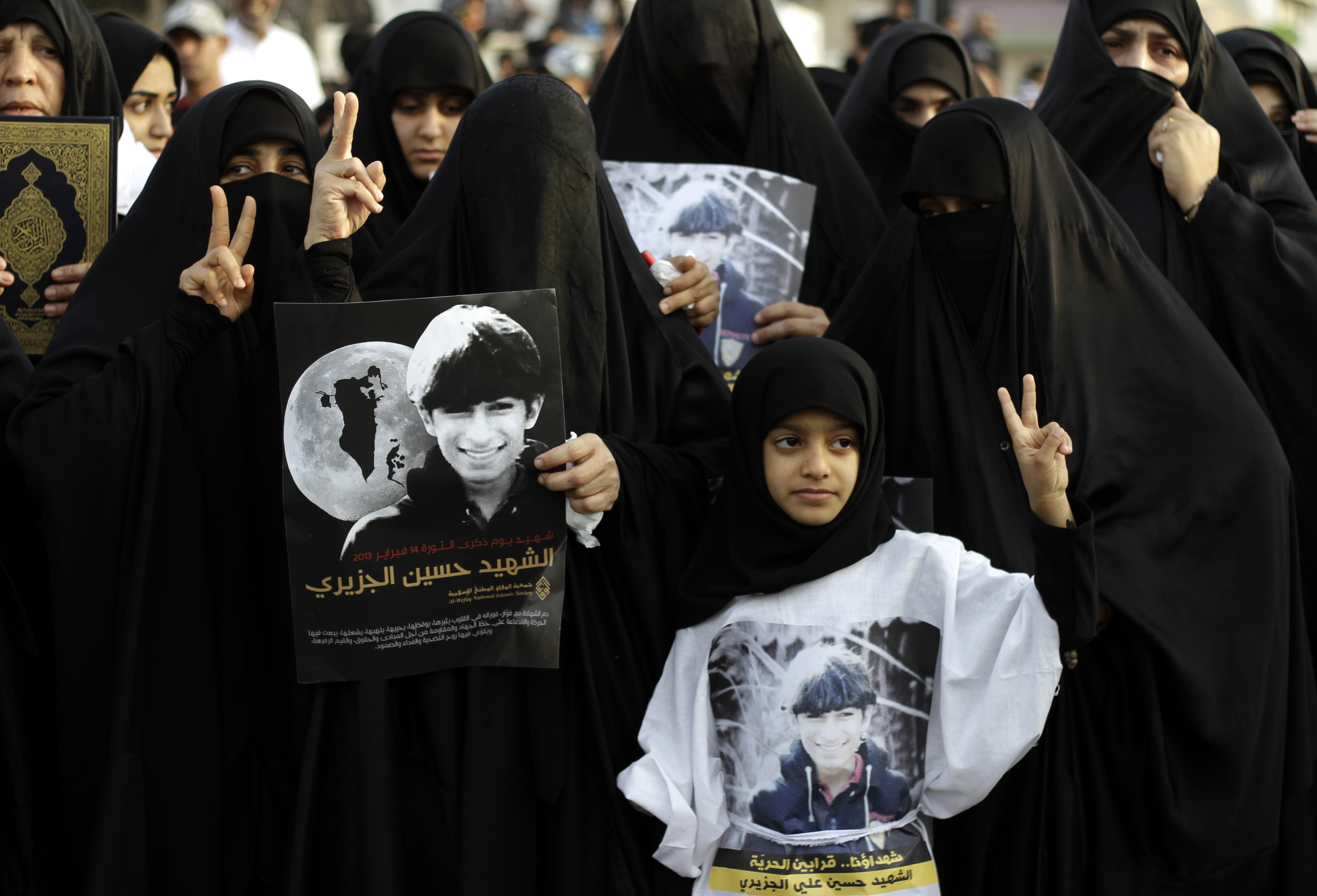 Bahraini women hold pictures of Hussein al-Jazeeri, 16, during a mourning procession in Daih, Bahrain, on Feb. 19, 2013