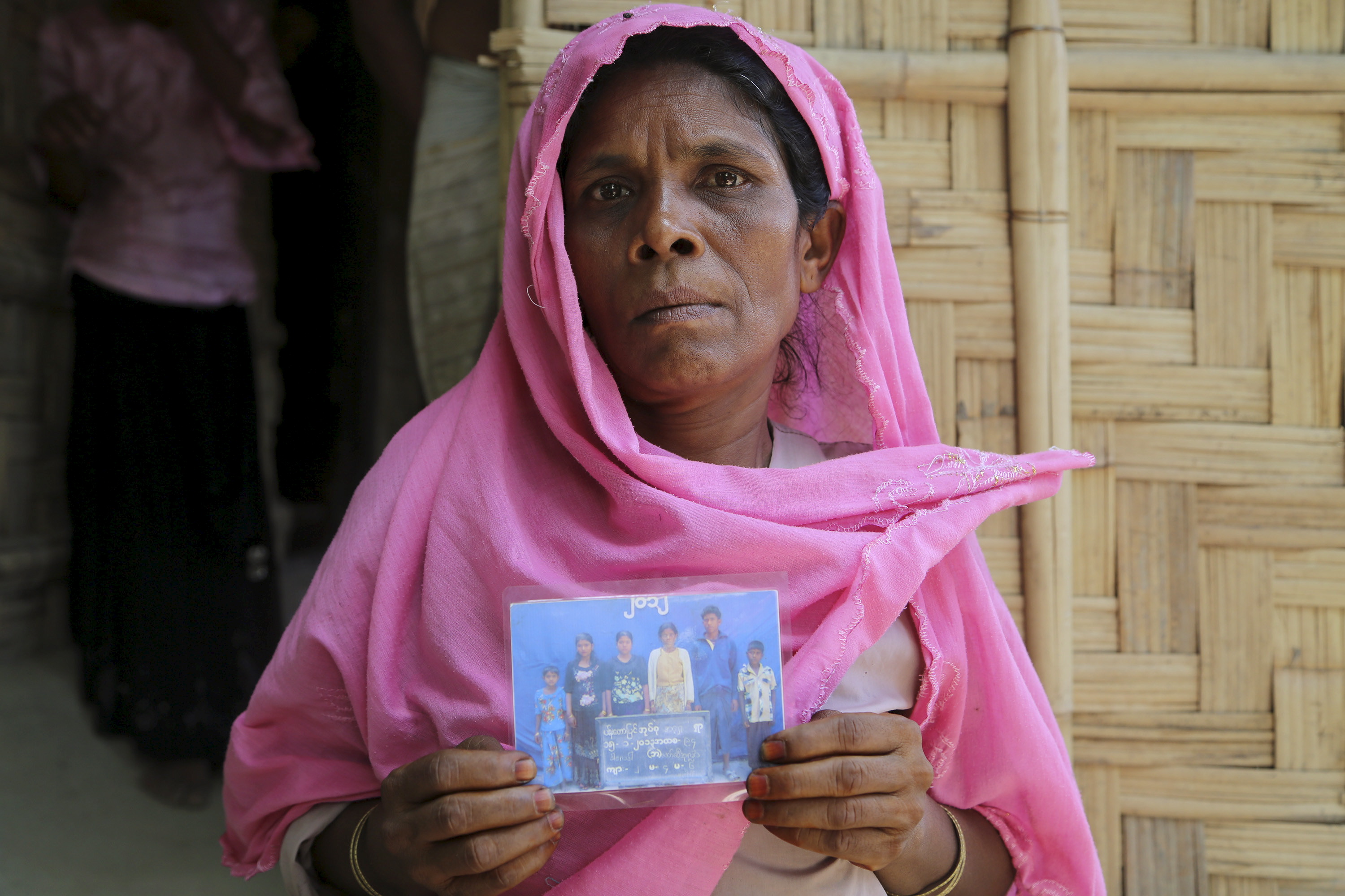 In this 7 June 2015 photo, Rohingya woman Se Tara, in Rakhine state, holds up a family photograph that shows her two missing children, aged 12 and 18, who had set out to sea in February 