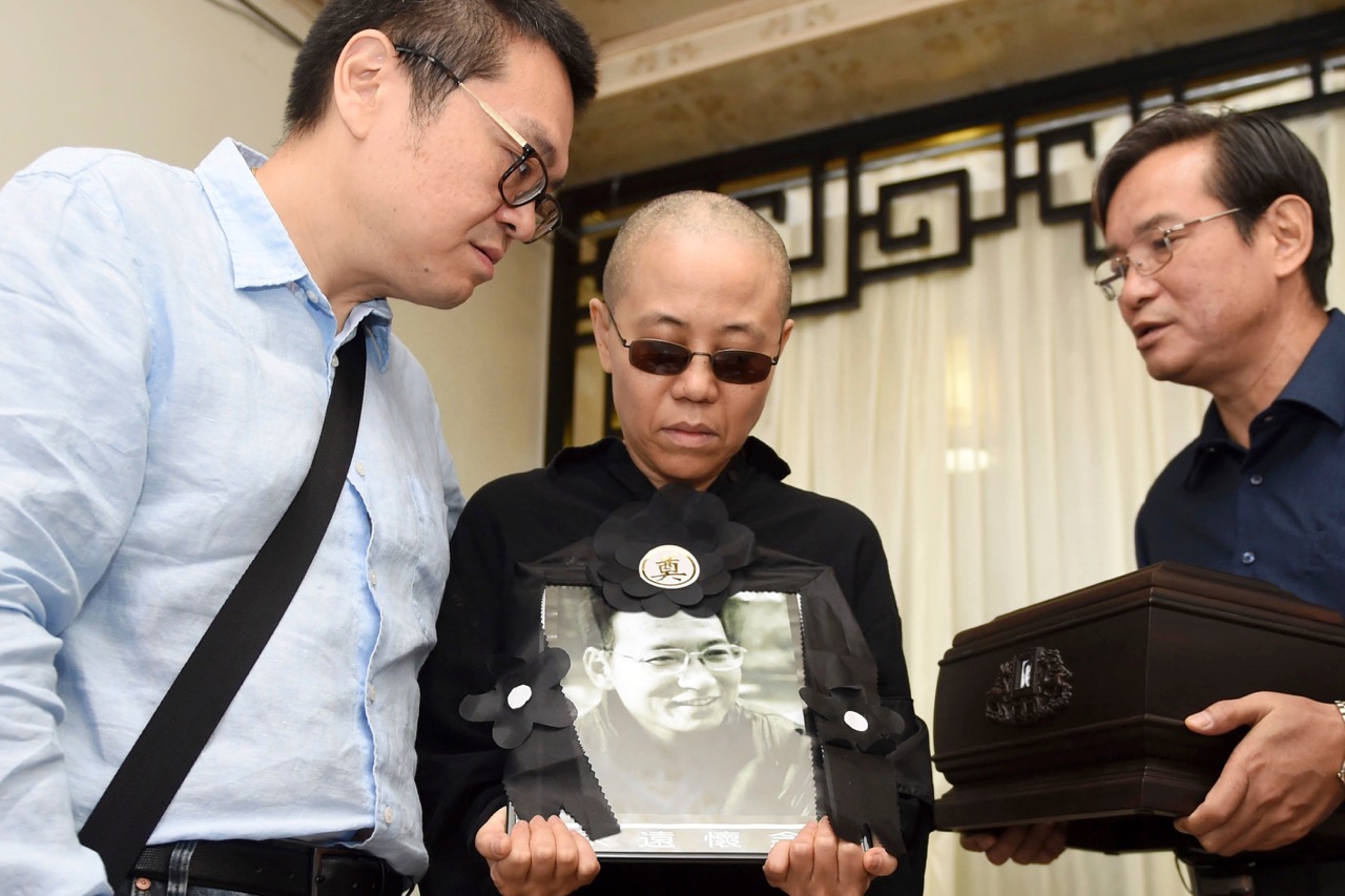 Liu Xia, center, holds a portrait of him during his funeral in Shenyang in northeastern China's, 15 July 2017. The photo shows, from left to right, Liu Hui, younger brother of Liu Xia, Liu Xia and Liu Xiaoxuan, younger brother of Liu Xiaobo holding his cremated remains
