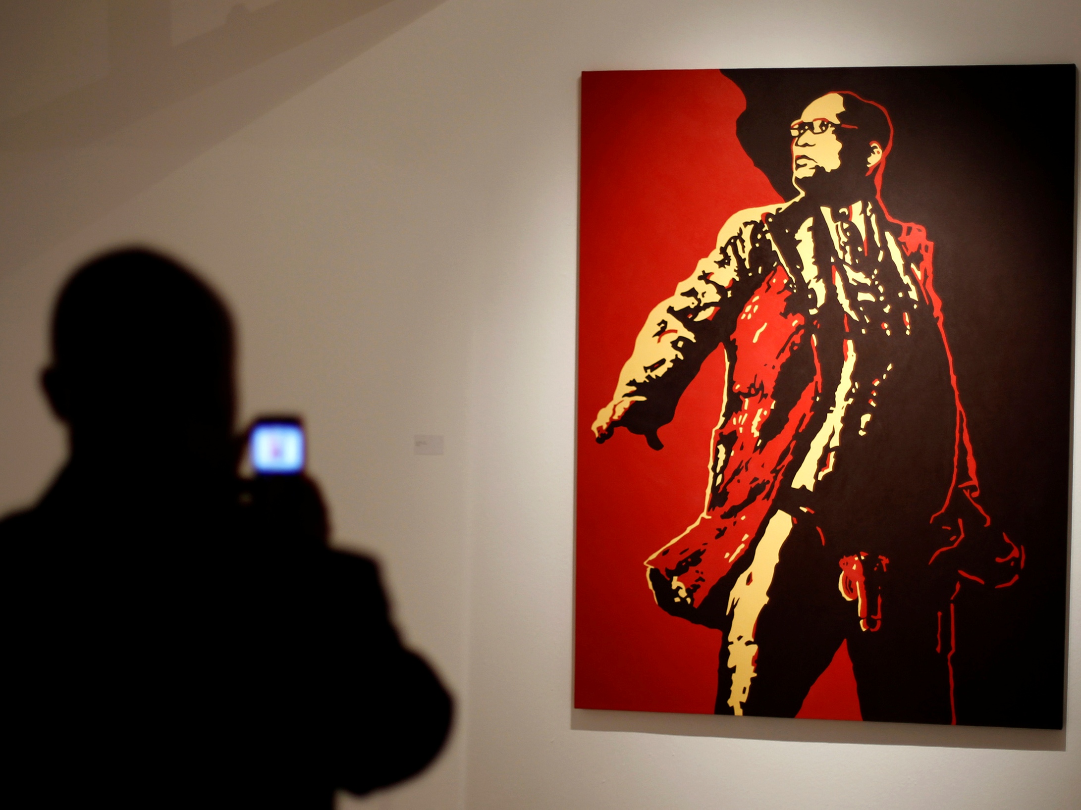 A visitor photographs a painting of South Africa's President Jacob Zuma at an exhibition in Johannesburg, 18 May 2012