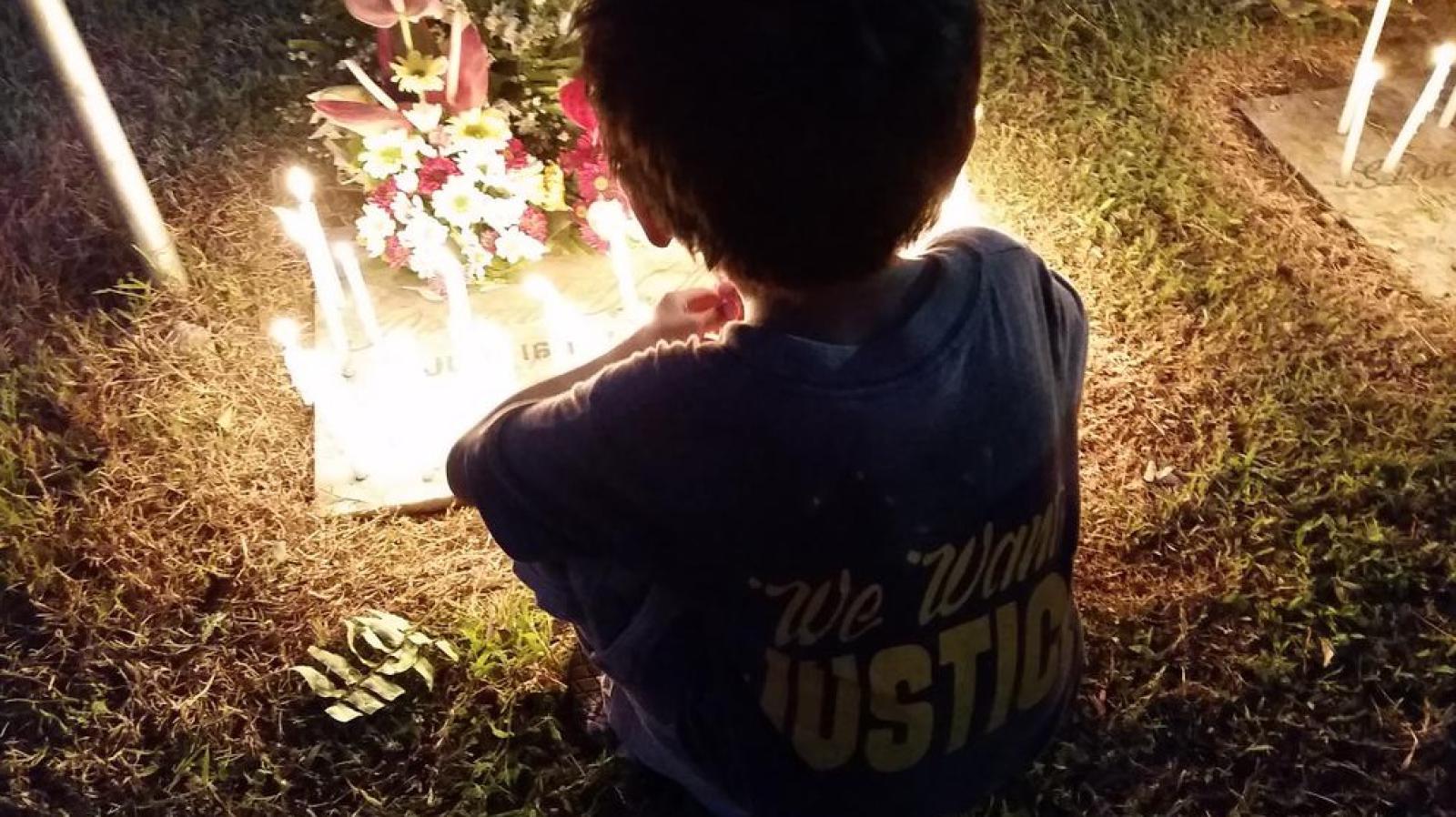 Un niño enciende velas en la tumba de las víctimas de la Masacre de Ampatuan el 23 de noviembre en la ciudad de General Santos, Filipinas 