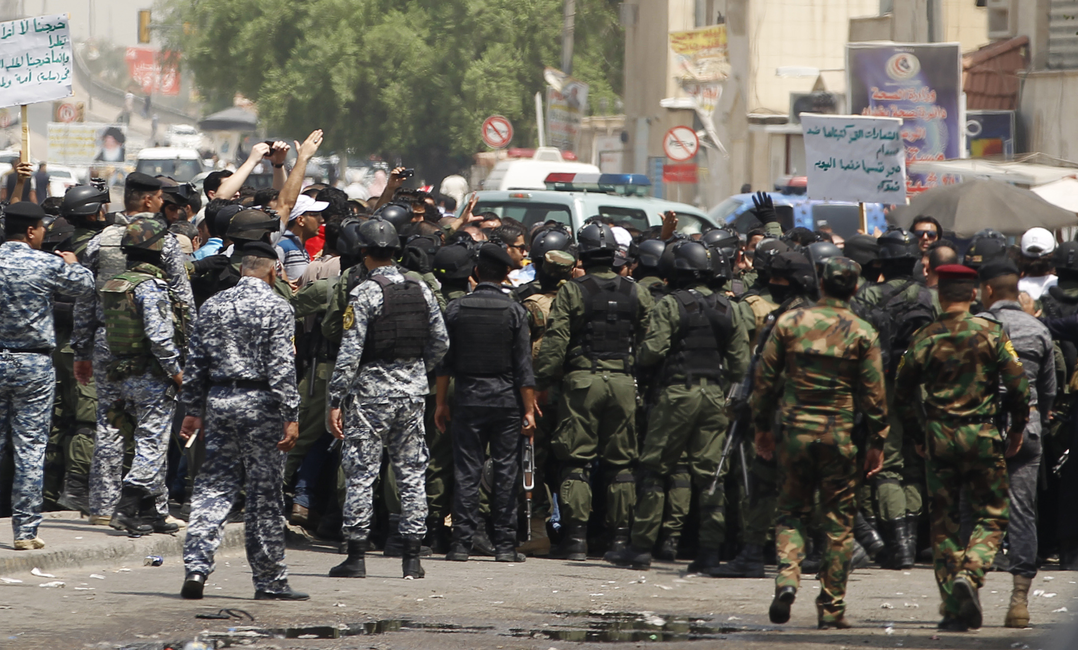 Members of the Iraqi security forces prevent protesters from passing through a cordoned road which leads to Al-Tahrir Square during the demonstration in Baghdad
