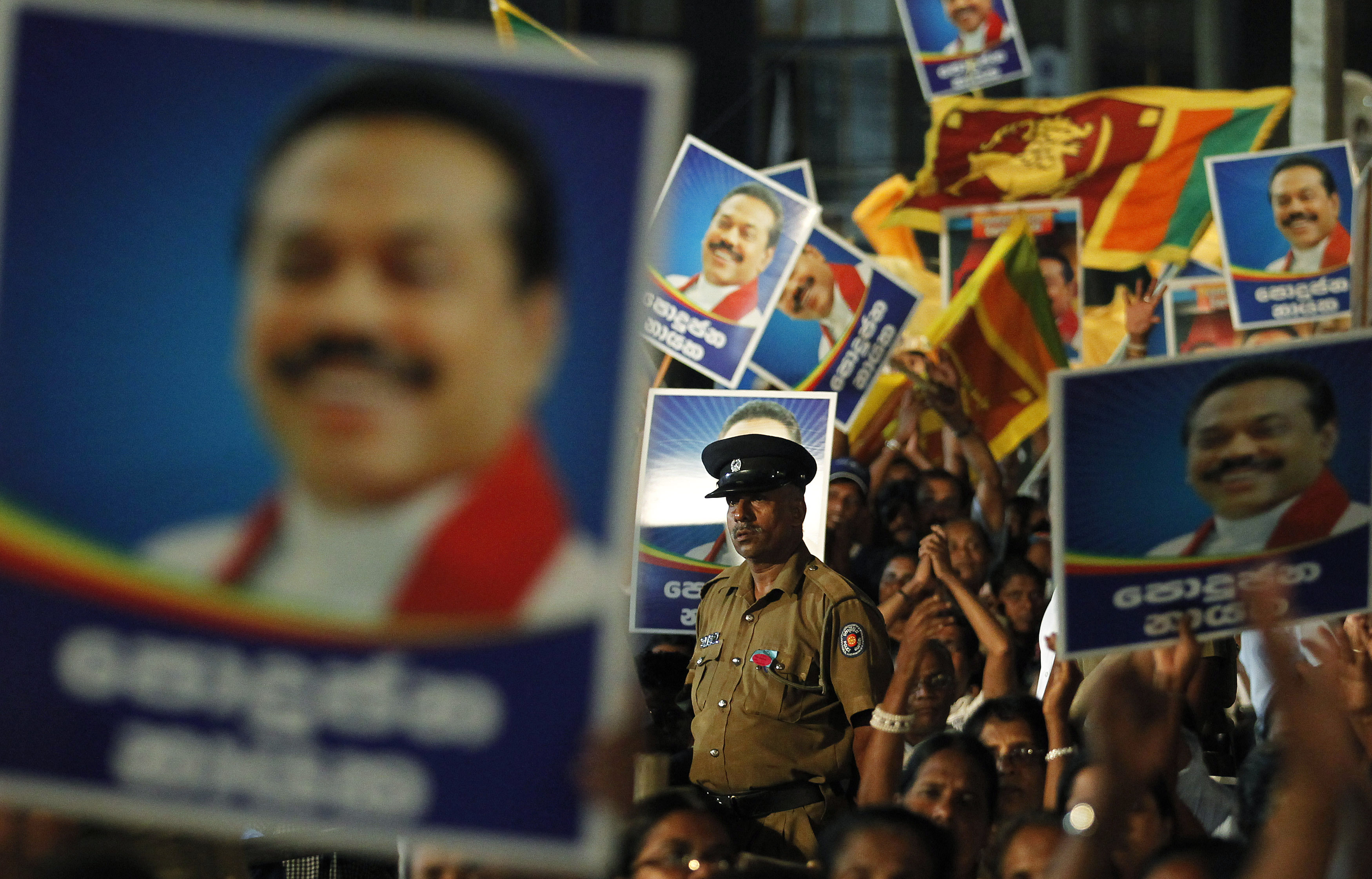 A police officer stands guard among images of then president Mahinda Rajapaksa during his final rally ahead of the presidential election in Piliyandala 5 January 2015