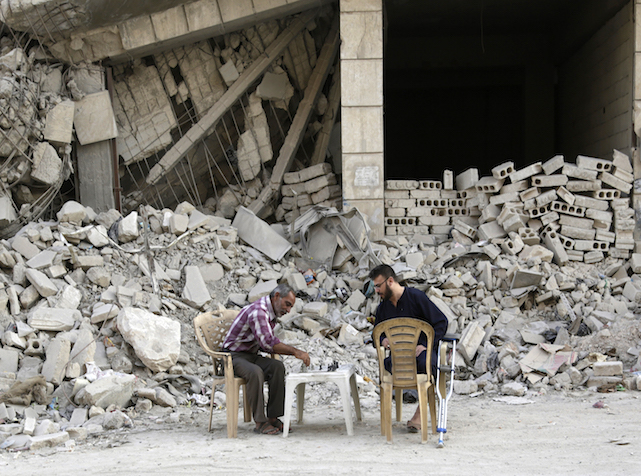 رجلان يلعبان الشطرنج أمام مبنى متضرر في المنطقة معرة النعمان في إدلب التي يسيطر عليها الثوار, 19 أكتوبر 2015