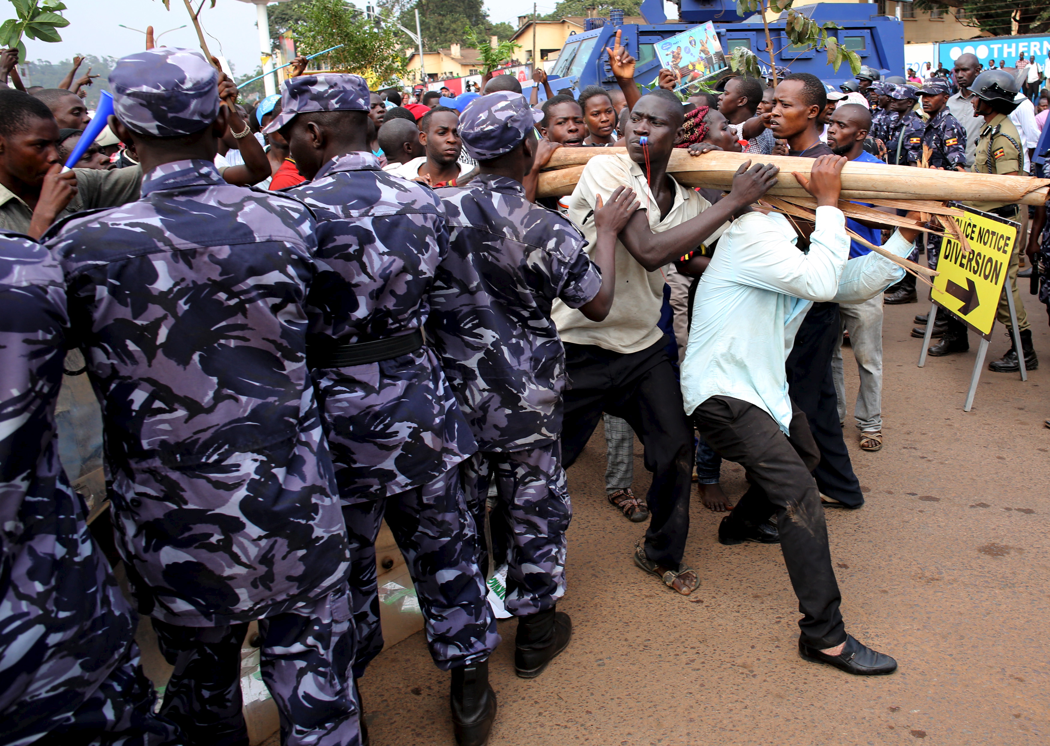 Opposition supporters walk in front of policemen in Kampala, Uganda, 15 February 2016