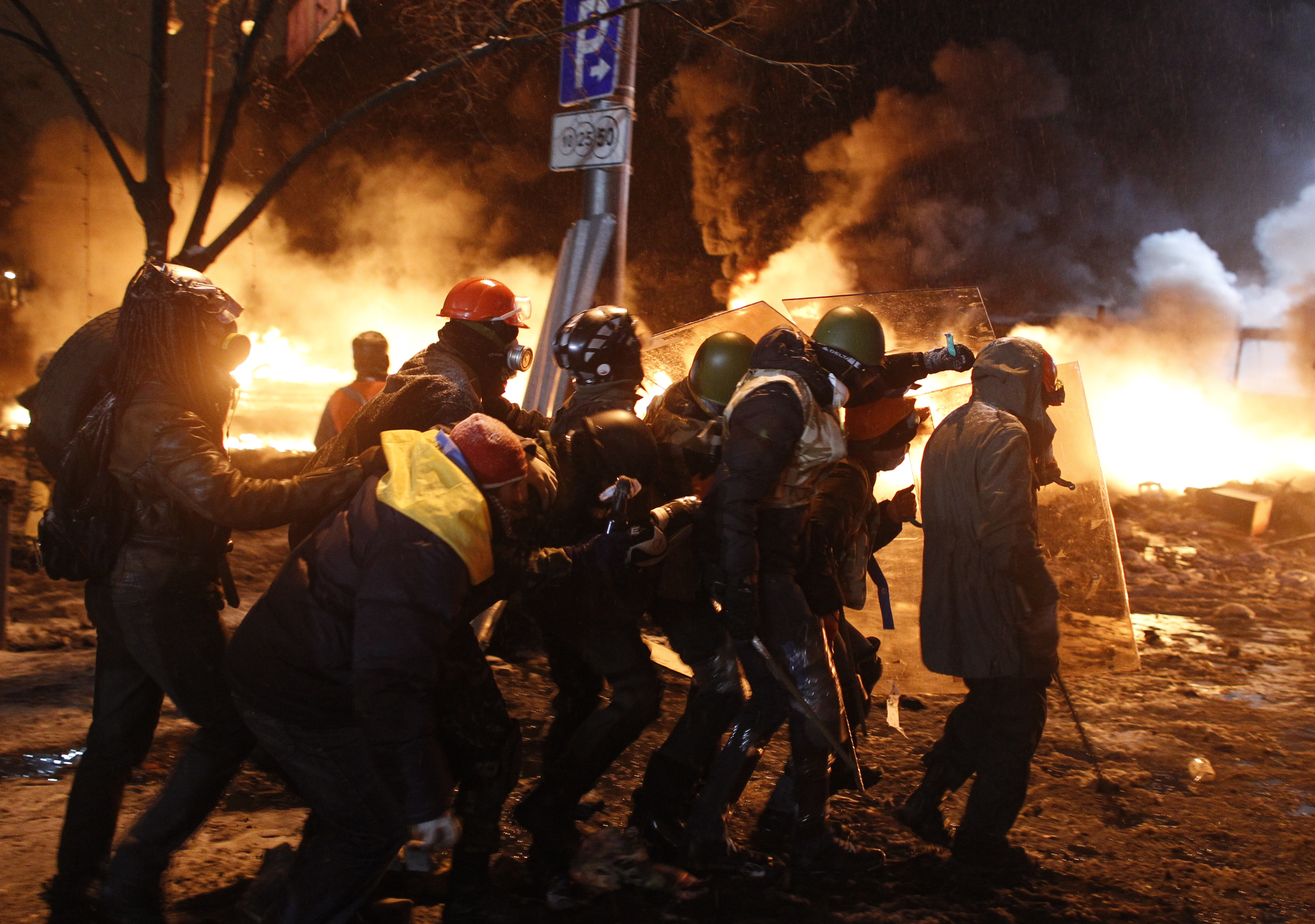 Pro-European protesters take cover behind shields during clashes with riot police in Kyiv, 22 January 2014.