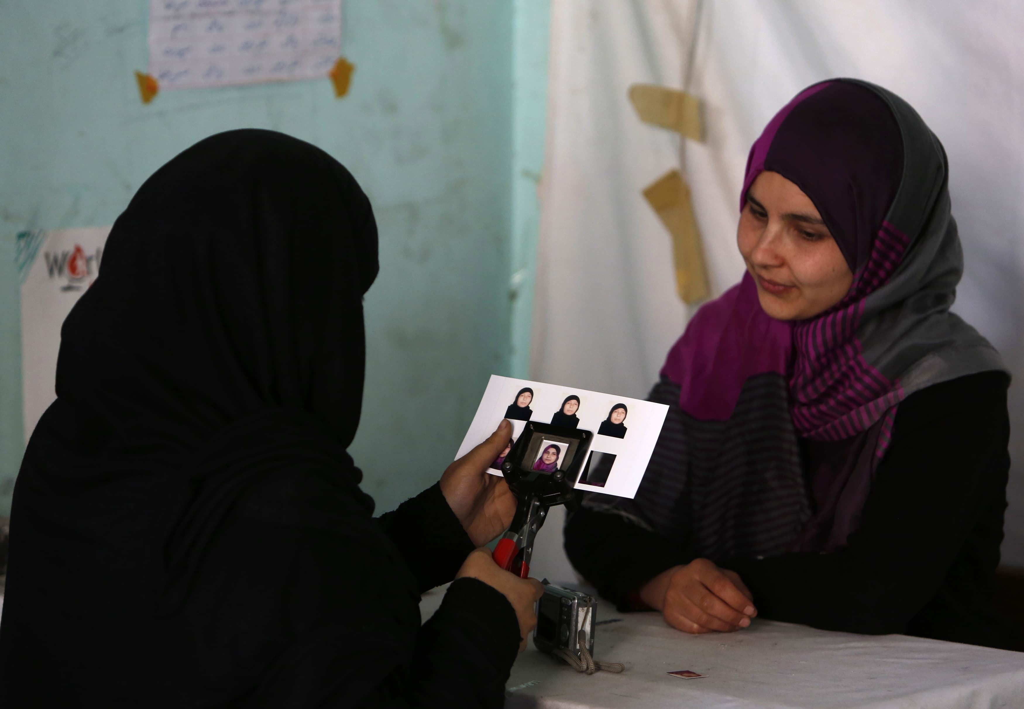 An Afghan girl waits to receive her voter card at a voter registration center in Kabul, 20 March 2014. The presidential elections will be held on 5 April, REUTERS/Mohammad Ismail