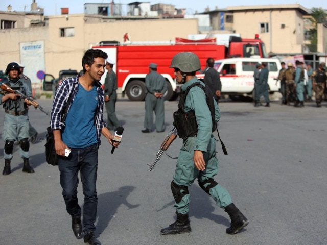 A reporter is seen with a member of the Afghan security forces after a suicide car bombing attack in Kabul, Afghanistan, 19 May 2015, AP Photo/Rahmat Gul