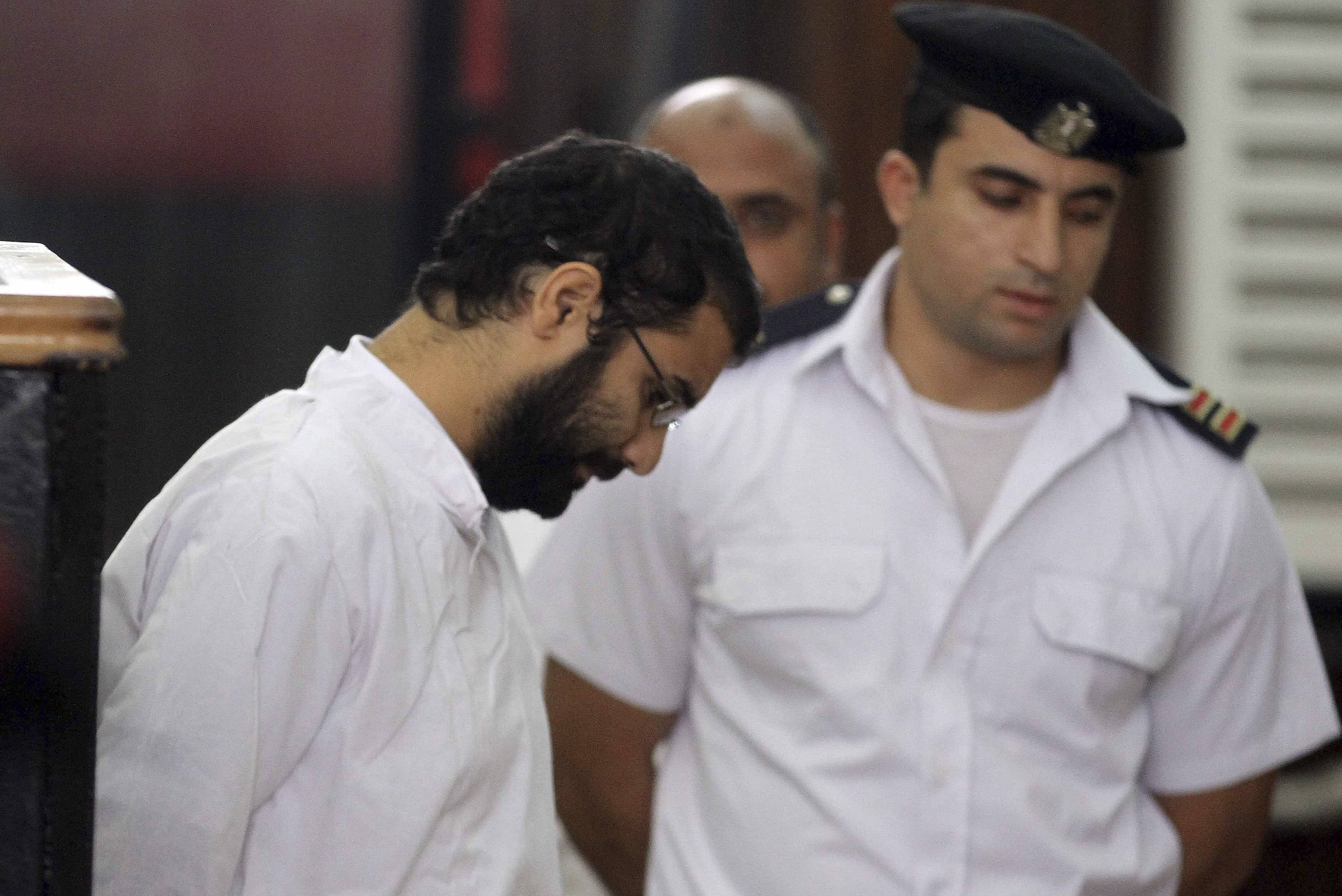 Activist Alaa Abdel Fattah stands in front of a police officer at a court during his trial in Cairo, November 11, 2014, REUTERS/Al Youm Al Saabi Newspaper