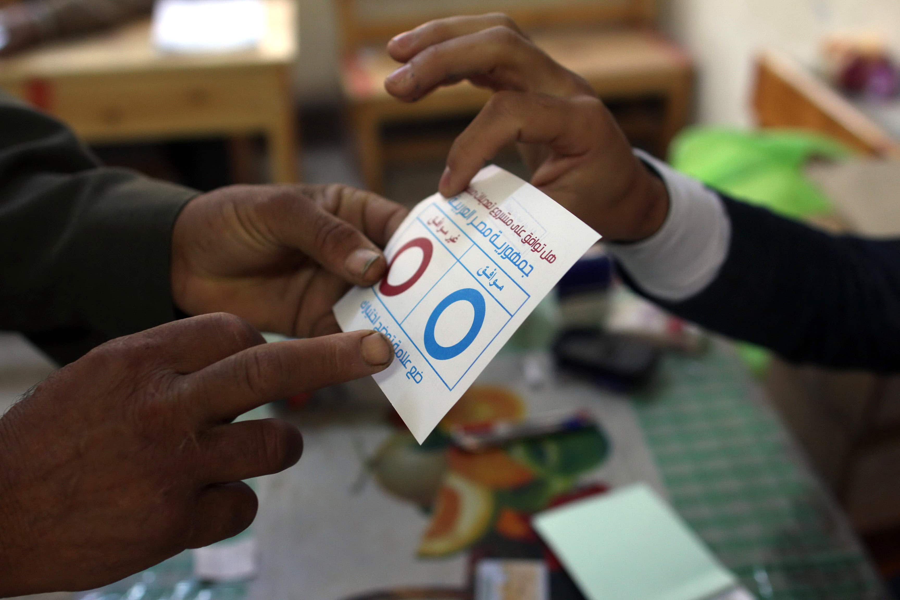 A judge shows a villager a ballot for the constitutional referendum inside a polling station in Dalga village of Minya, Egypt on 15 January 2014, AP Photo/Roger Anis, El Shorouk Newspaper