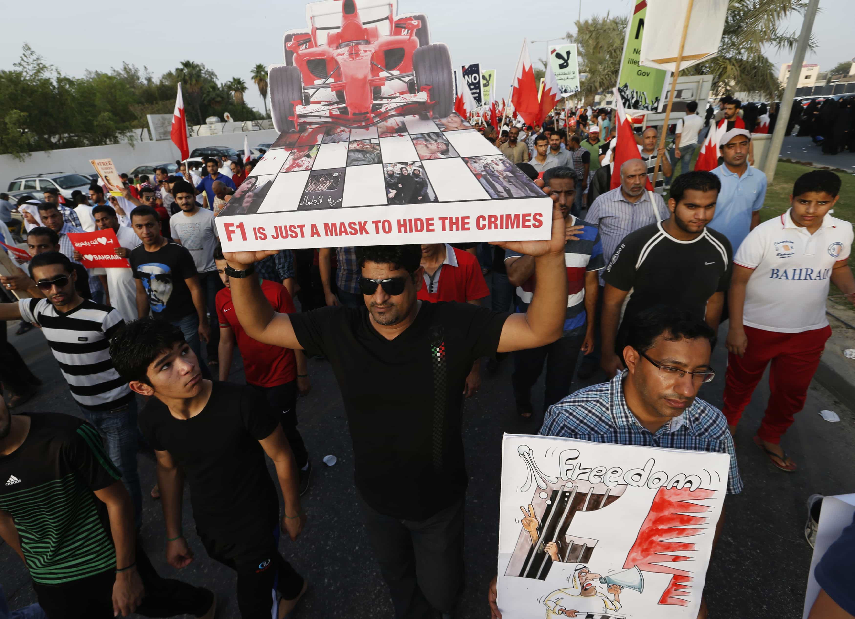 A protester (C) holds a placard shaped like a Formula One car as he participates in an anti-government rally organised by main opposition group Al Wefaq in Budaiya on 19 April 2013, REUTERS/Hamad I Mohammed