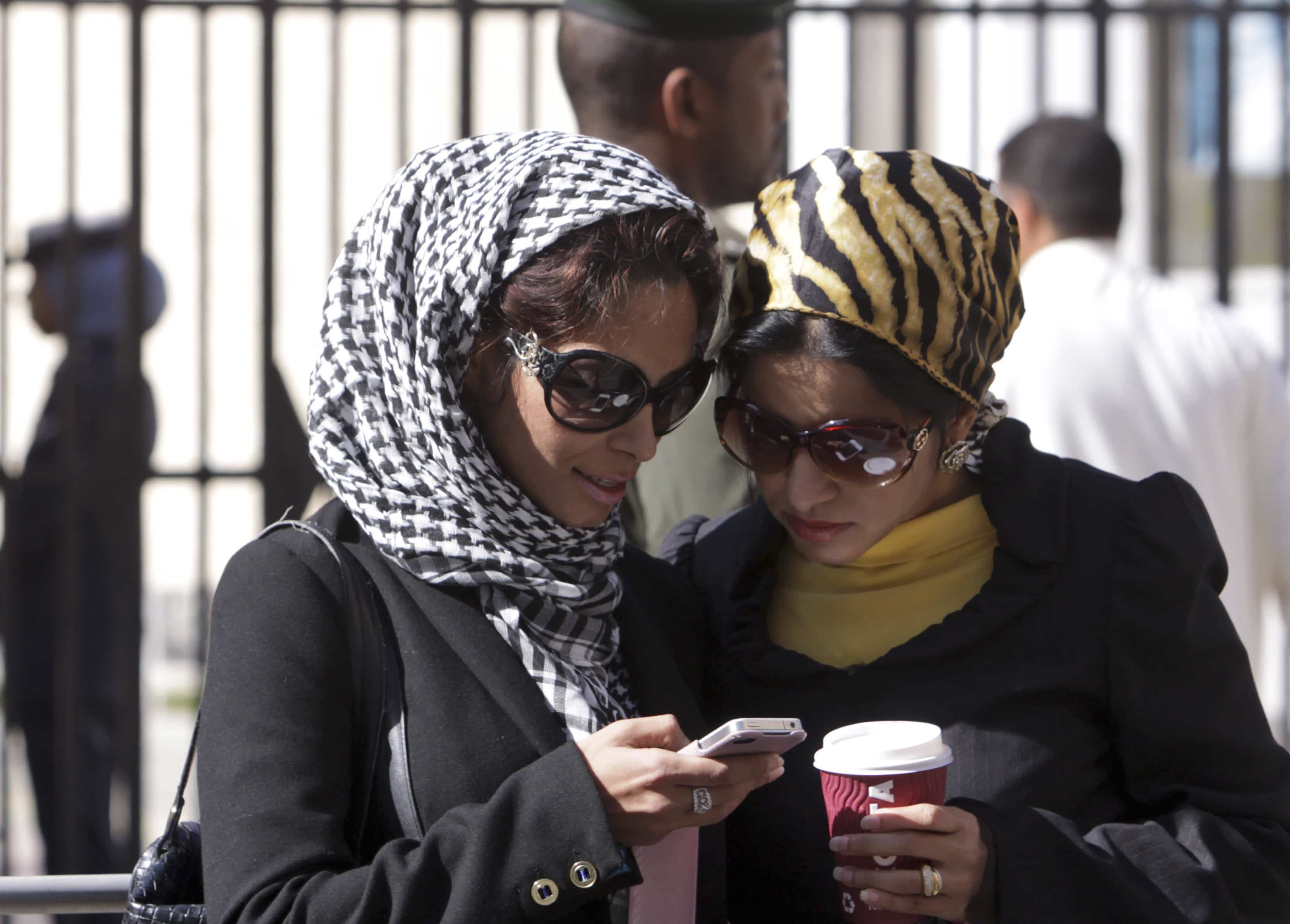 Two Bahraini women peer over a mobile phone in Manama in 2012, AP Photo/Hasan Jamali