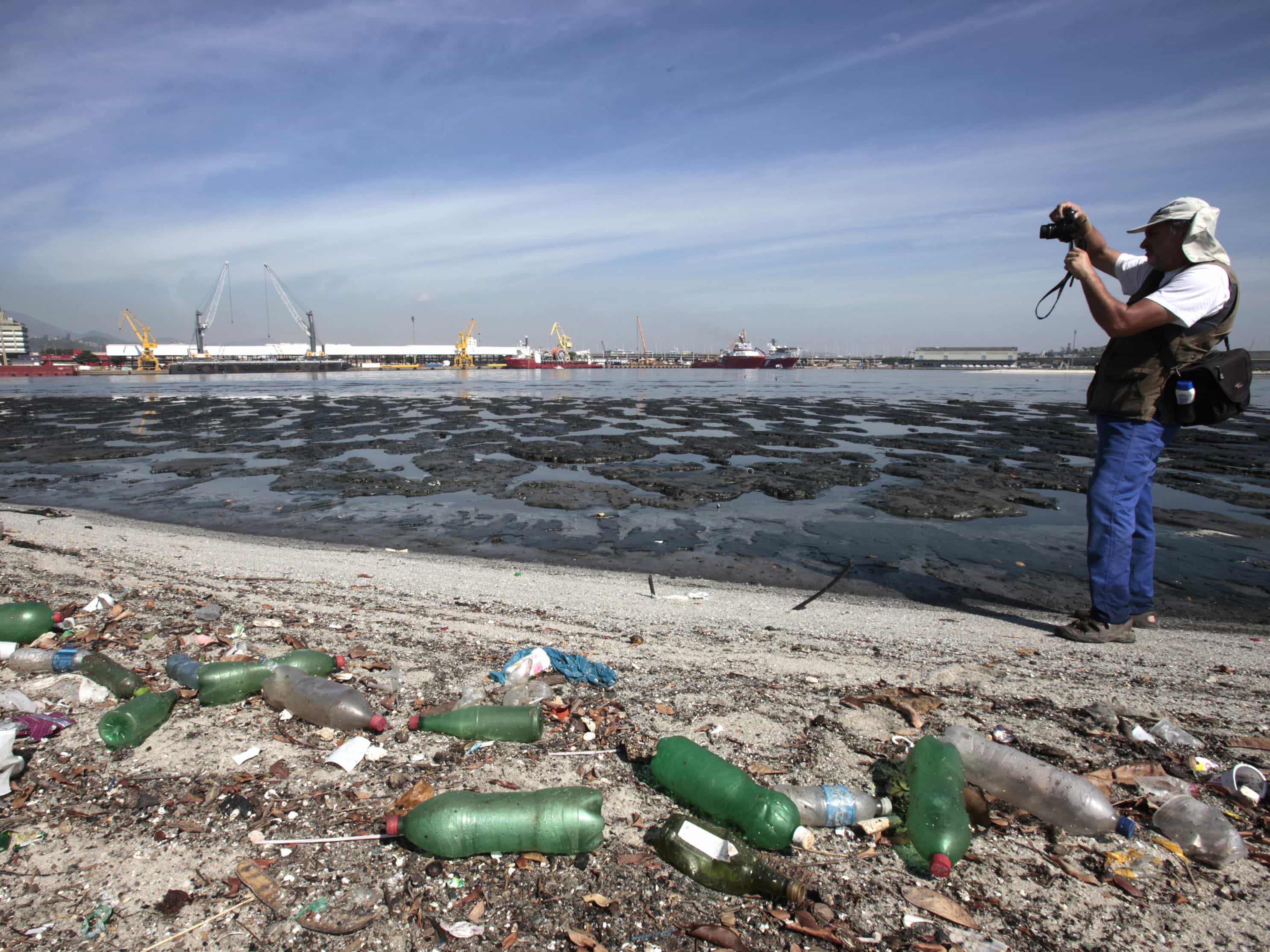 Brazilian biologist Mario Moscatelli takes pictures next to garbage in the Guanabara Bay in Rio de Janeiro, 12 March 2014, REUTERS/Sergio Moraes