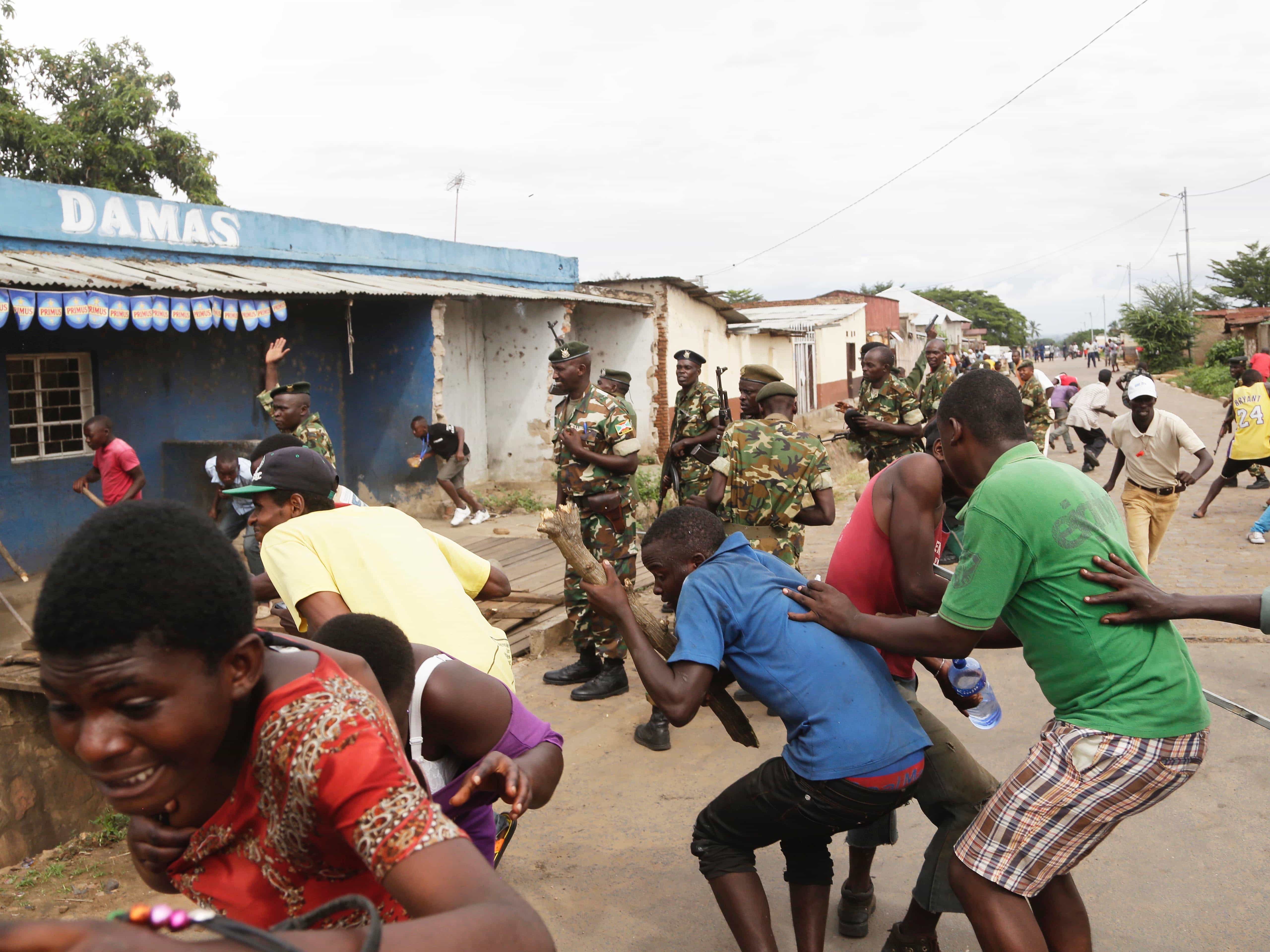 Demonstrators run from soldiers firing into the air to disperse a crowd of demonstrators who had cornered Jean Claude Niyonzima, a suspected member of the Imbonerakure in Bujumbura, Burundi, 7 May 2015, AP Photo/Jerome Delay