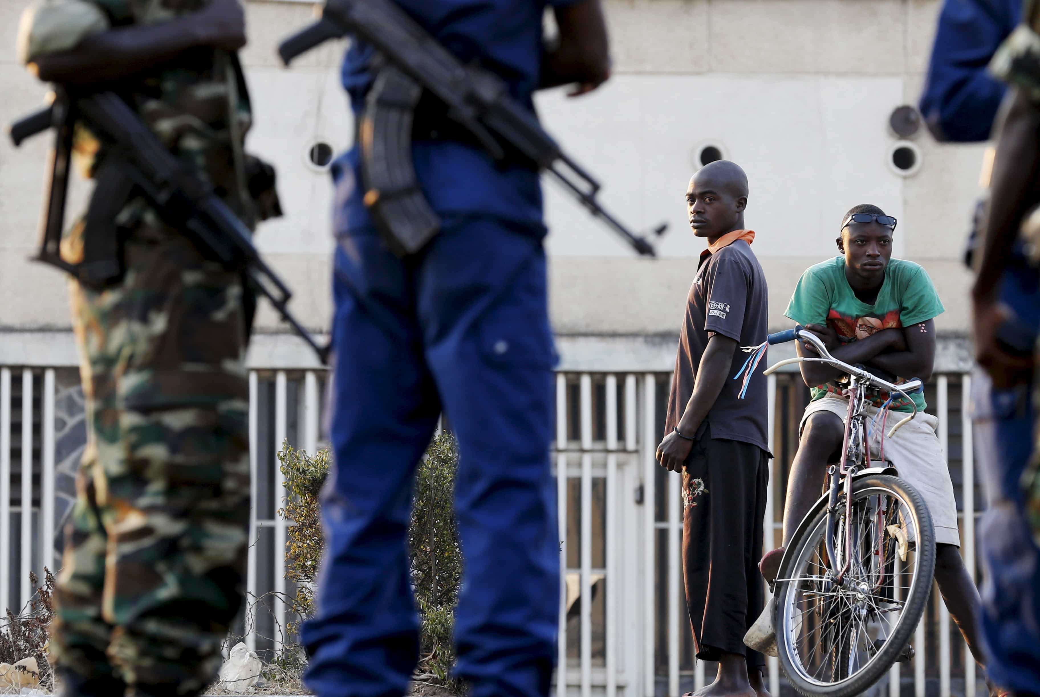 Residents look on as police and soldiers guard a voting station inBujumbura during Burundi's presidential elections, 21 July 2015, REUTERS/Mike Hutchings