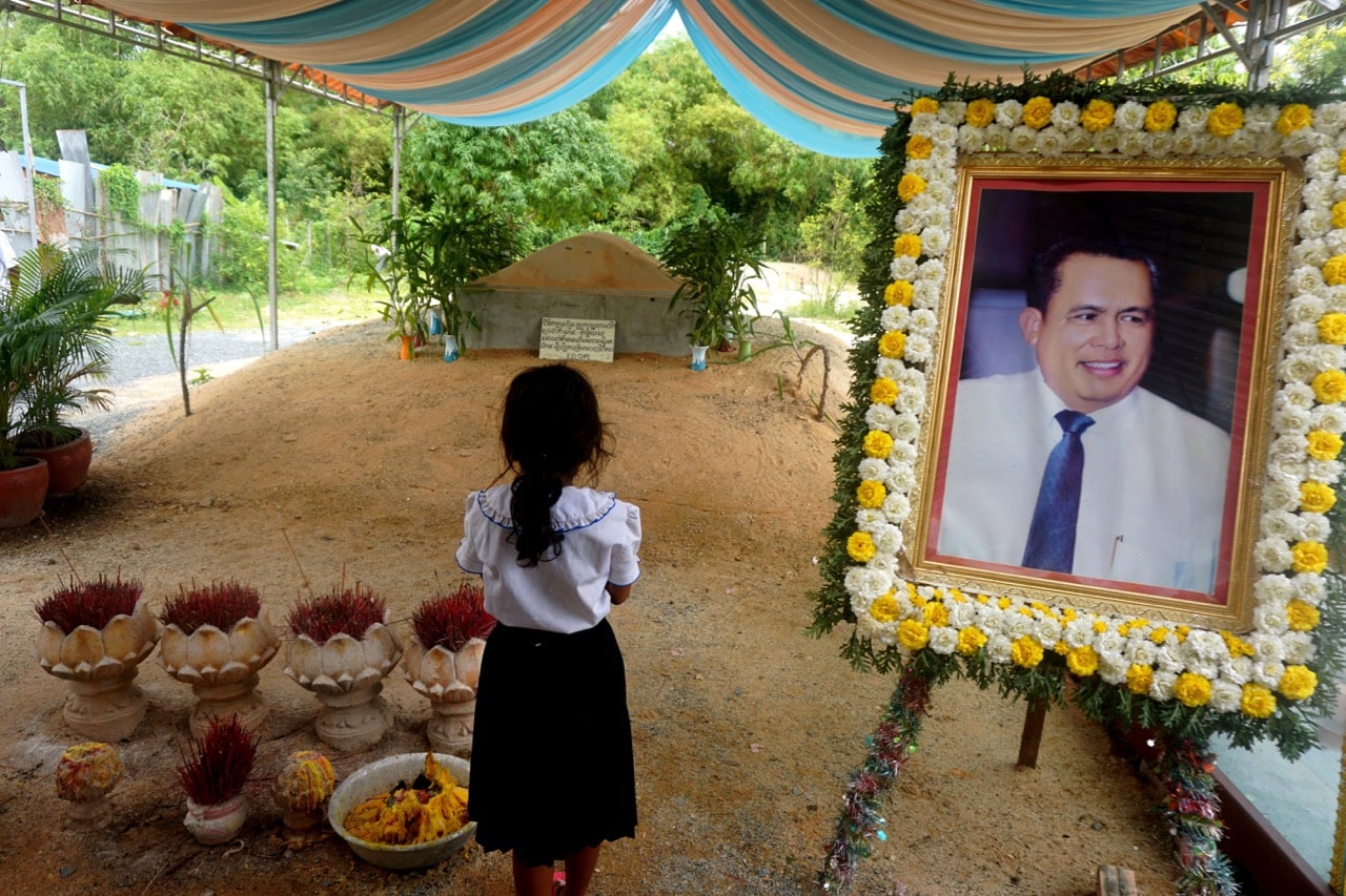 A girl stands by a portrait of Kem Ley, a Cambodian prominent political analyst, at his grave in Ang Takok, Cambodia, 20 November 2016, AP Photo/Denis Gray