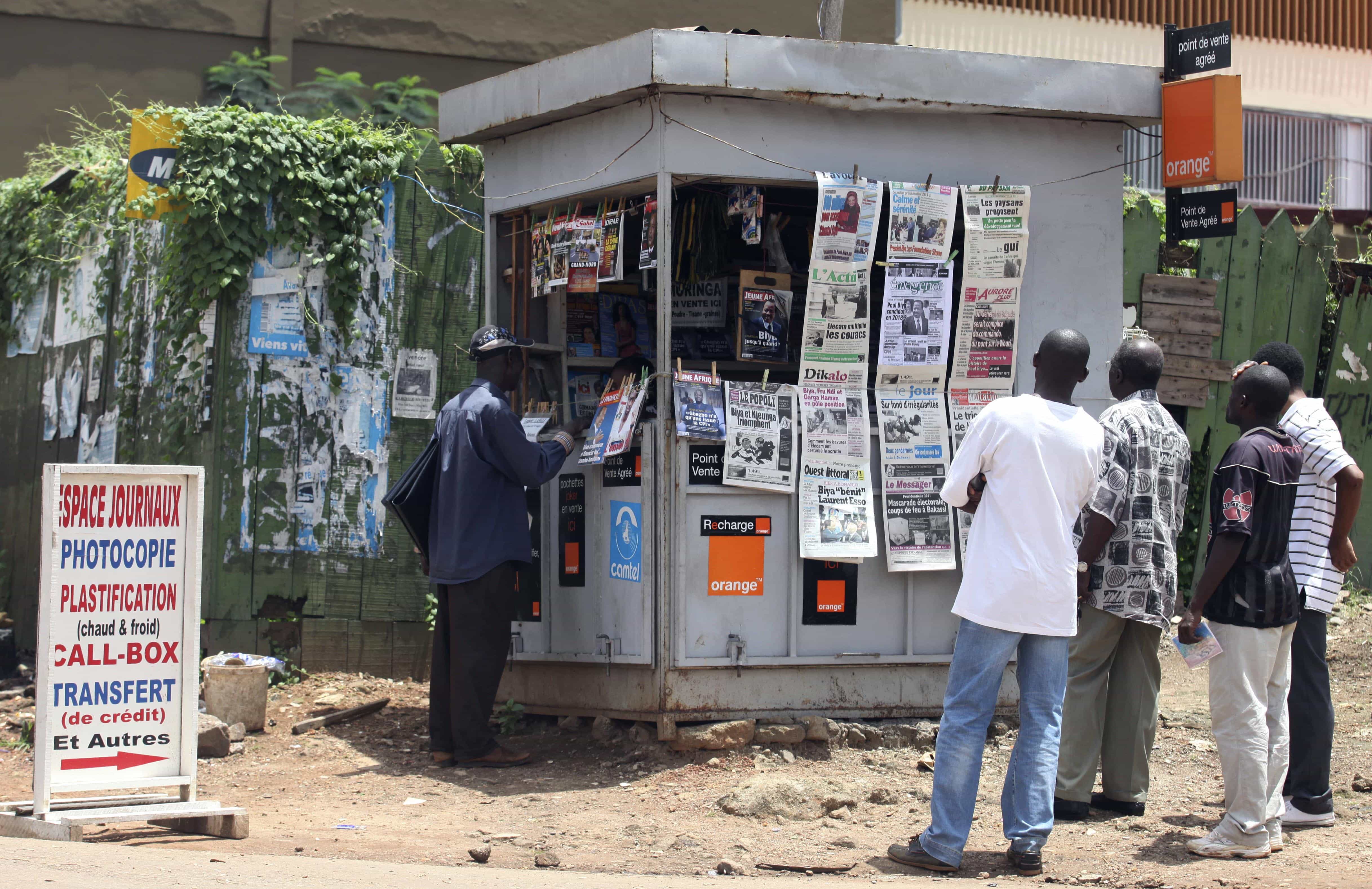 People gather to read newspapers with election headlines in Yaounde, 10 October 2011., AP Photo/Sunday Alamba