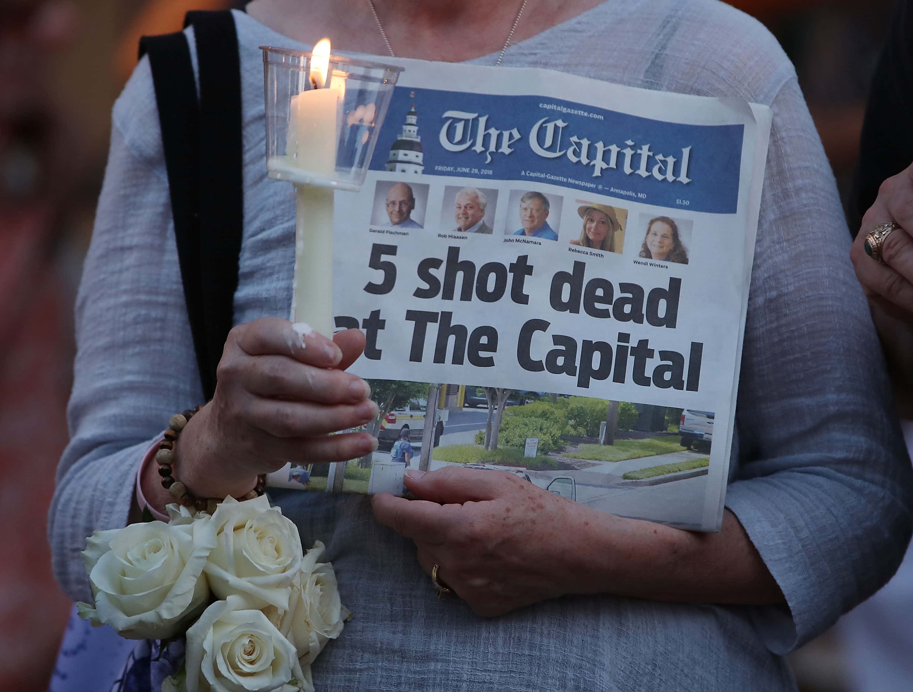 A women holds a copy of the Capital Gazette newpaper during a candlelight vigil to honor the 5 people who were shot and killed at the paper, Annapolis, United States, 2018, Mark Wilson/Getty Images