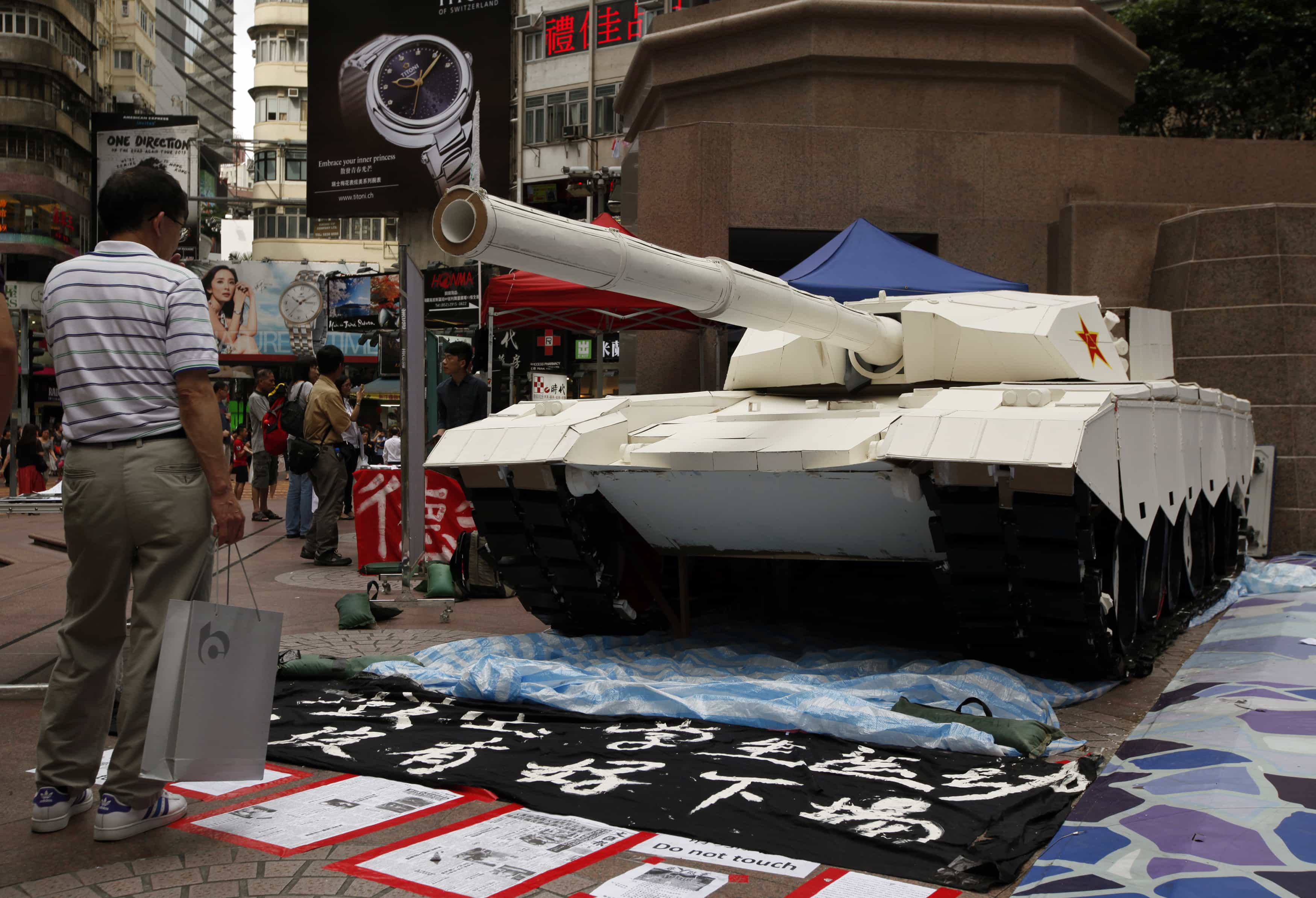 A shopper stands in front of a mock tank imitating those used during the 1989 crackdown in Tiananmen Square. Image taken in Hong Kong, 3 June 2014, REUTERS/Bobby Yip