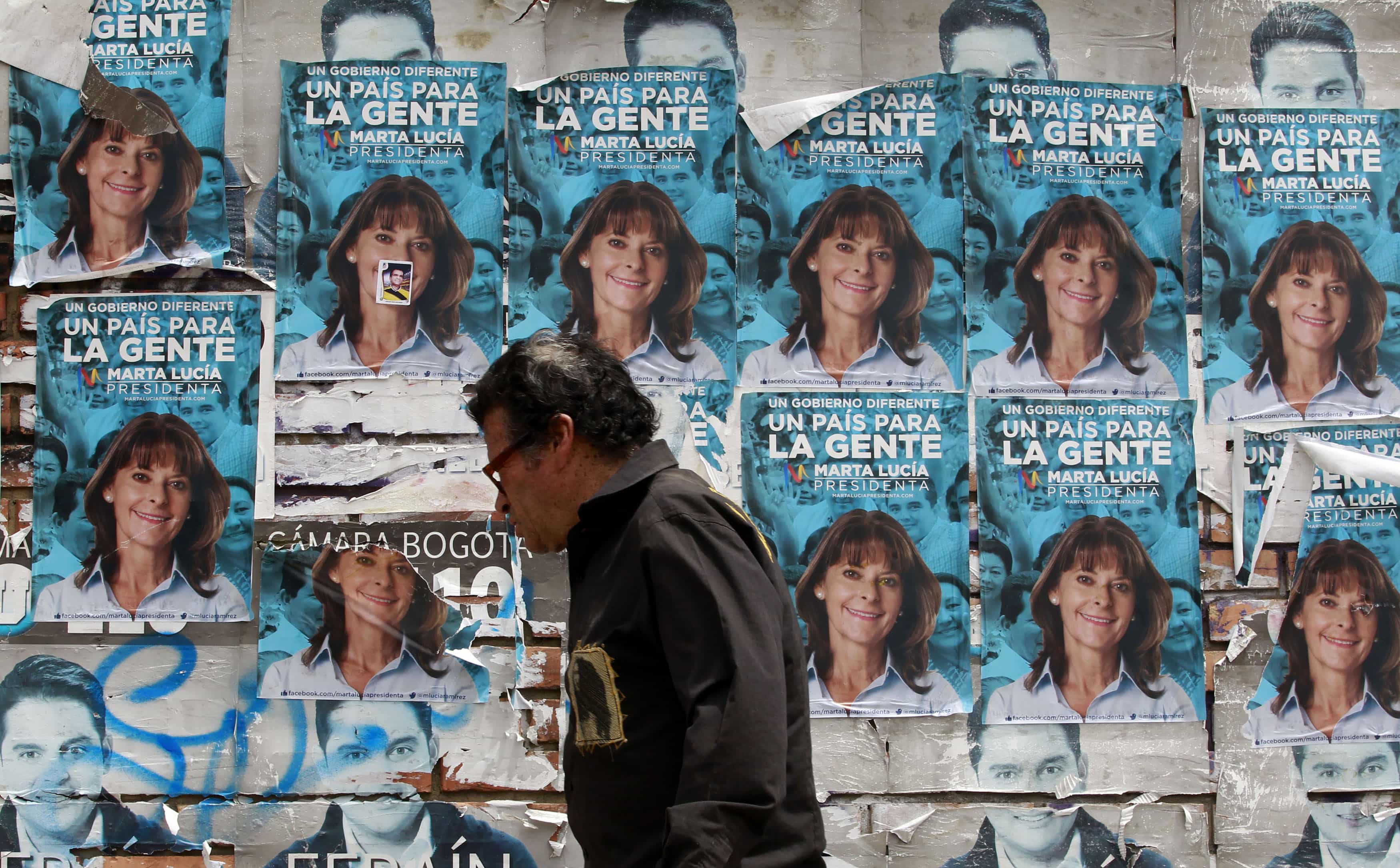 A man walks past posters of Conservative Party presidential candidate Marta Lucia Ramirez in Bogota May 22, 2014, REUTERS/Jose Miguel Gomez