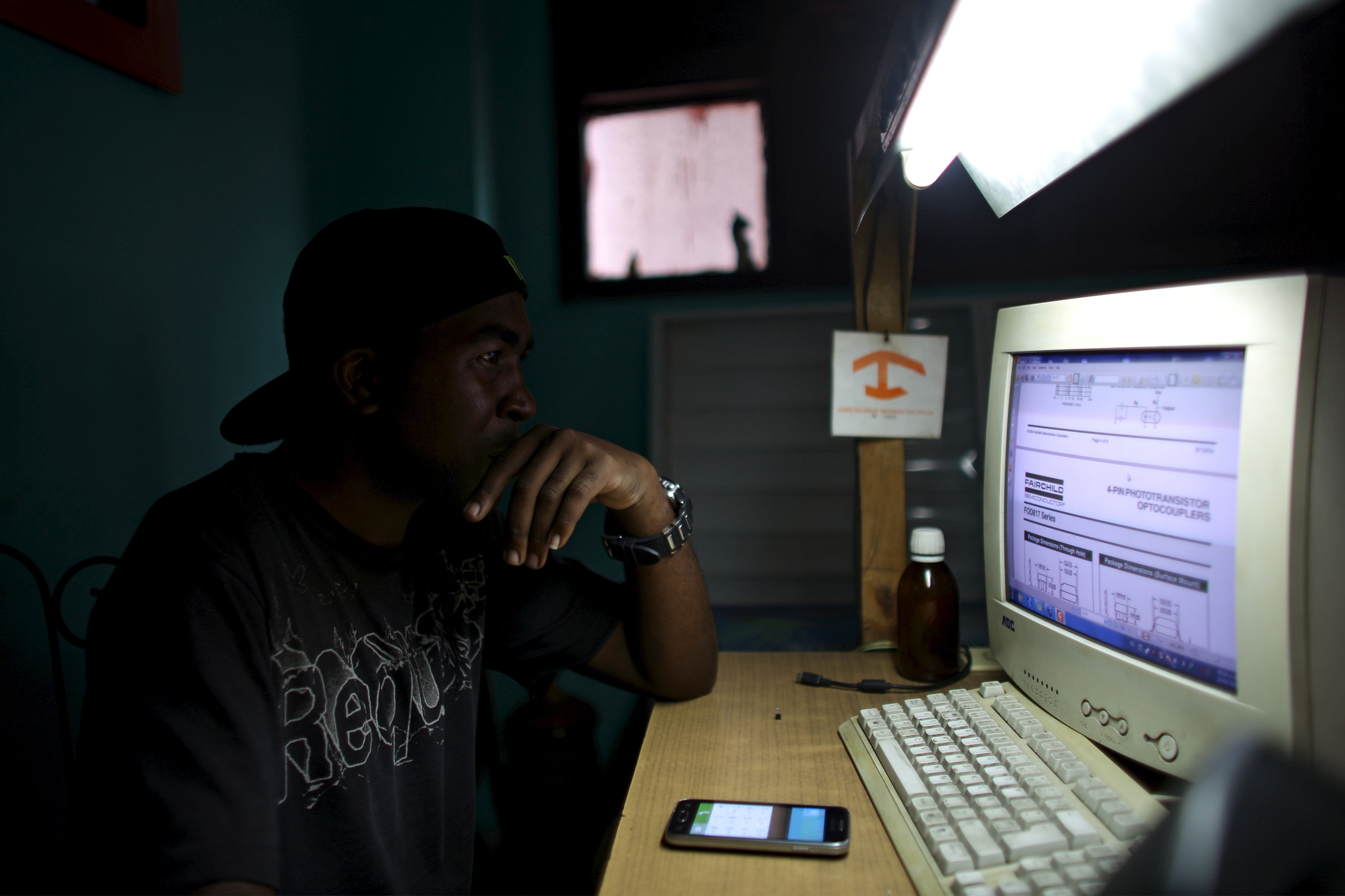 An informatics technician is pictured at the mobile phone repair shop where he works in Havana, 23 February 2016, REUTERS/Alexandre Meneghini
