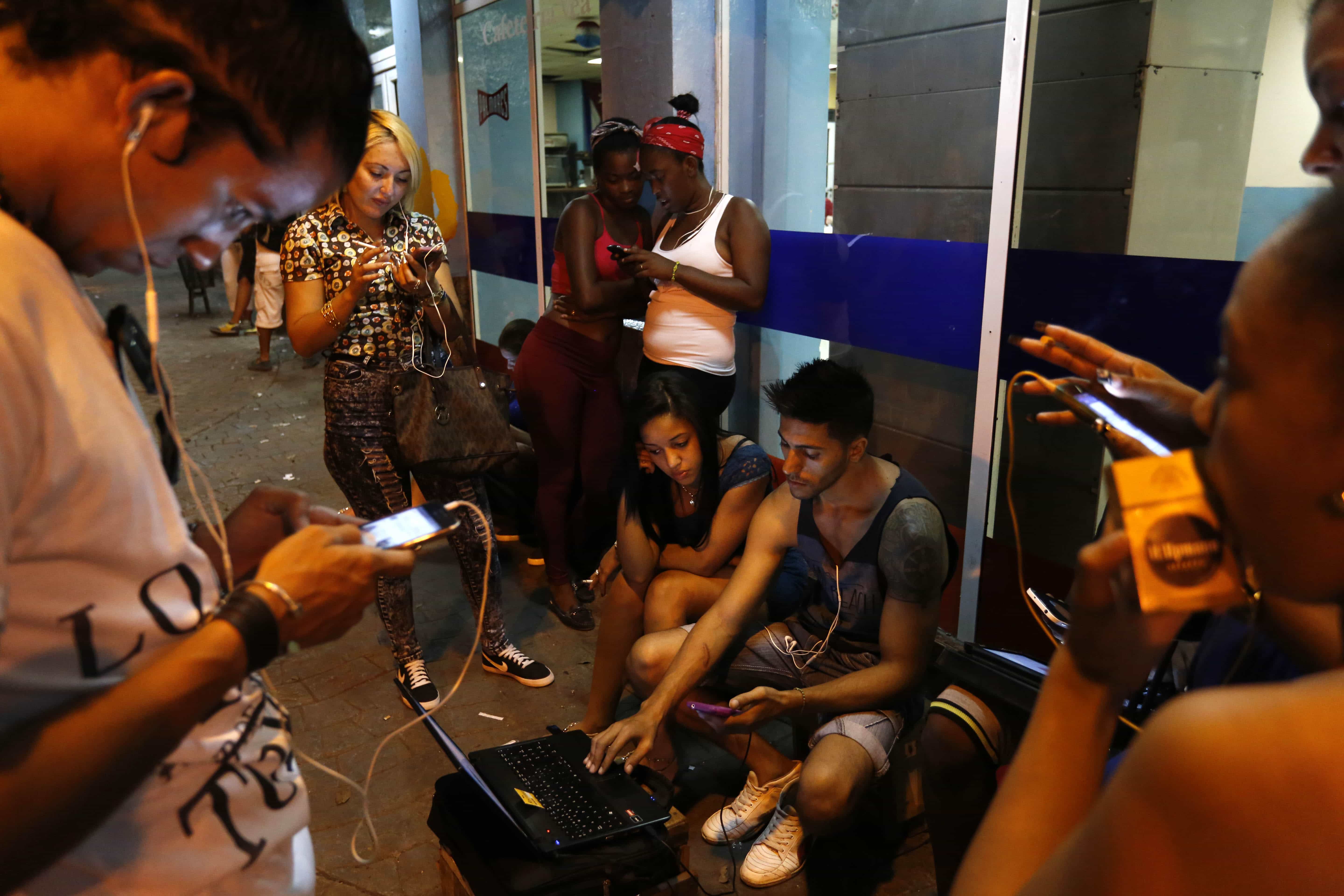 People connect to a WiFi hot spot in Havana, Cuba, AP Photo/Desmond Boylan