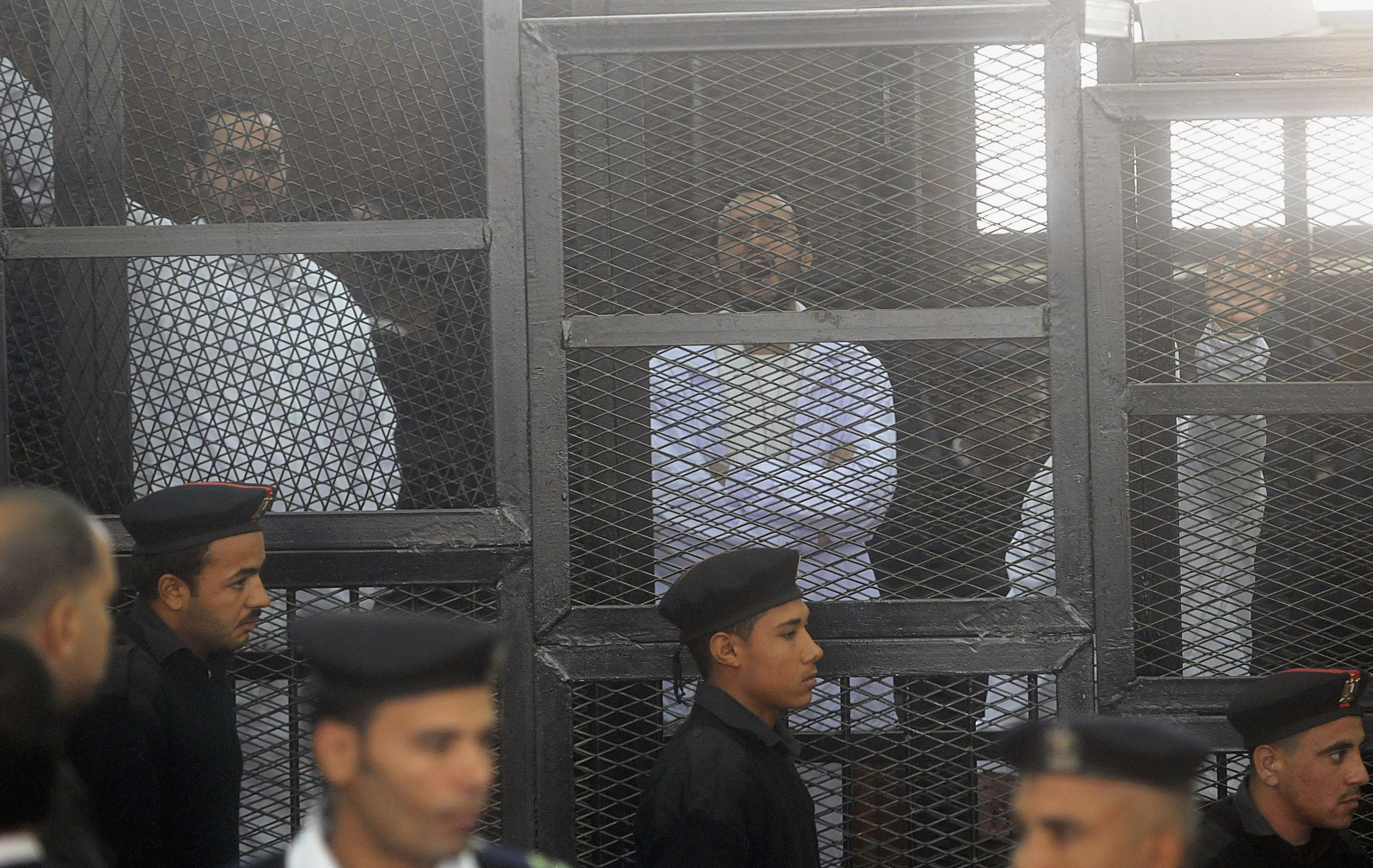 Political activists Ahmed Maher (R), Ahmed Douma (C) and Mohamed Adel, founder of 6 April movement, look on from behind bars in Abdeen court in Cairo on 22 December 2013, REUTERS/Stringer