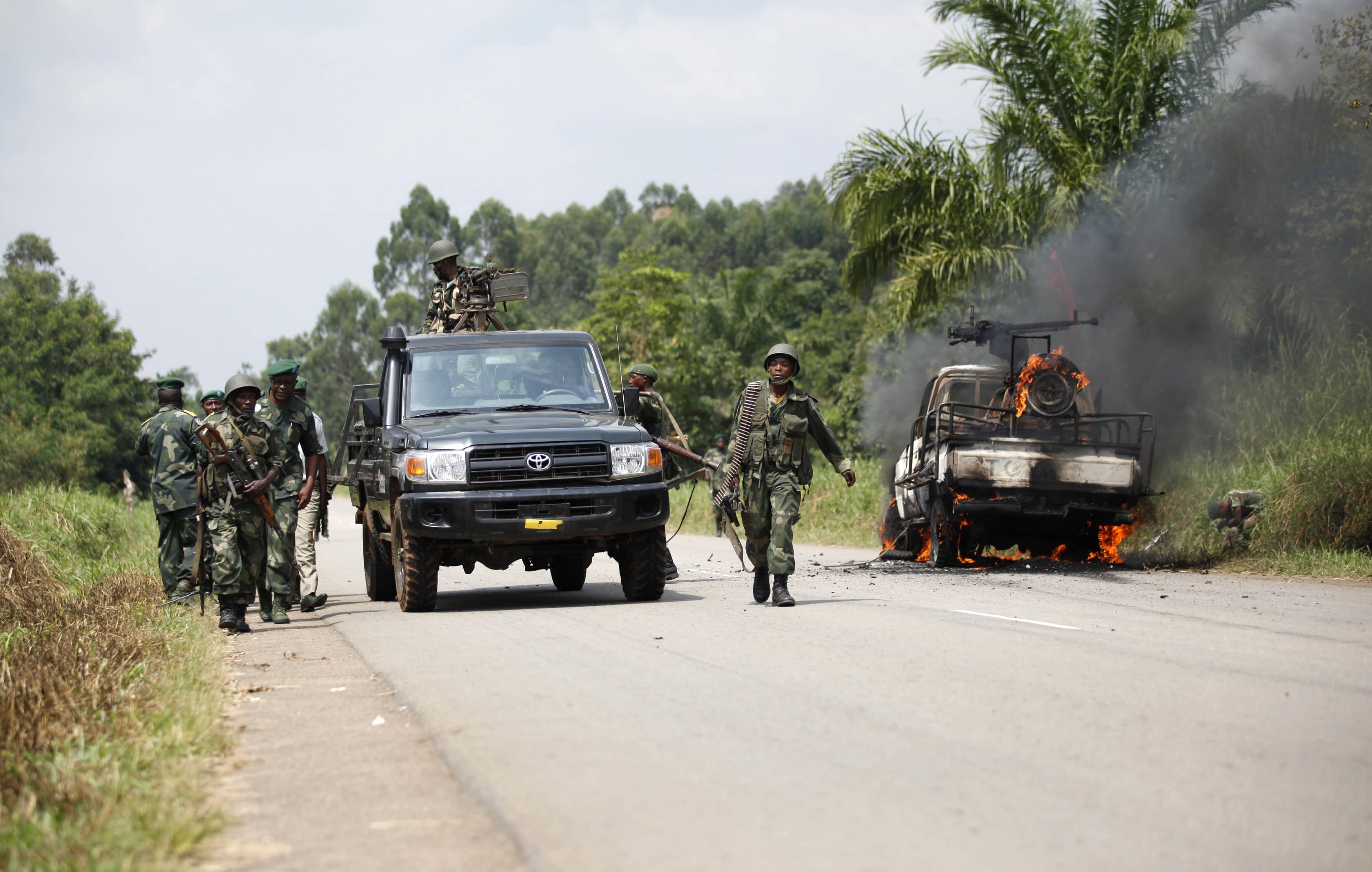 Congolese soldiers from the Armed Forces of the Democratic Republic of Congo (FARDC) stand next to their burning vehicle after an ambush near the village of Mavivi in North Kivu province, 2 January 2014. , REUTERS/Kenny Katombe