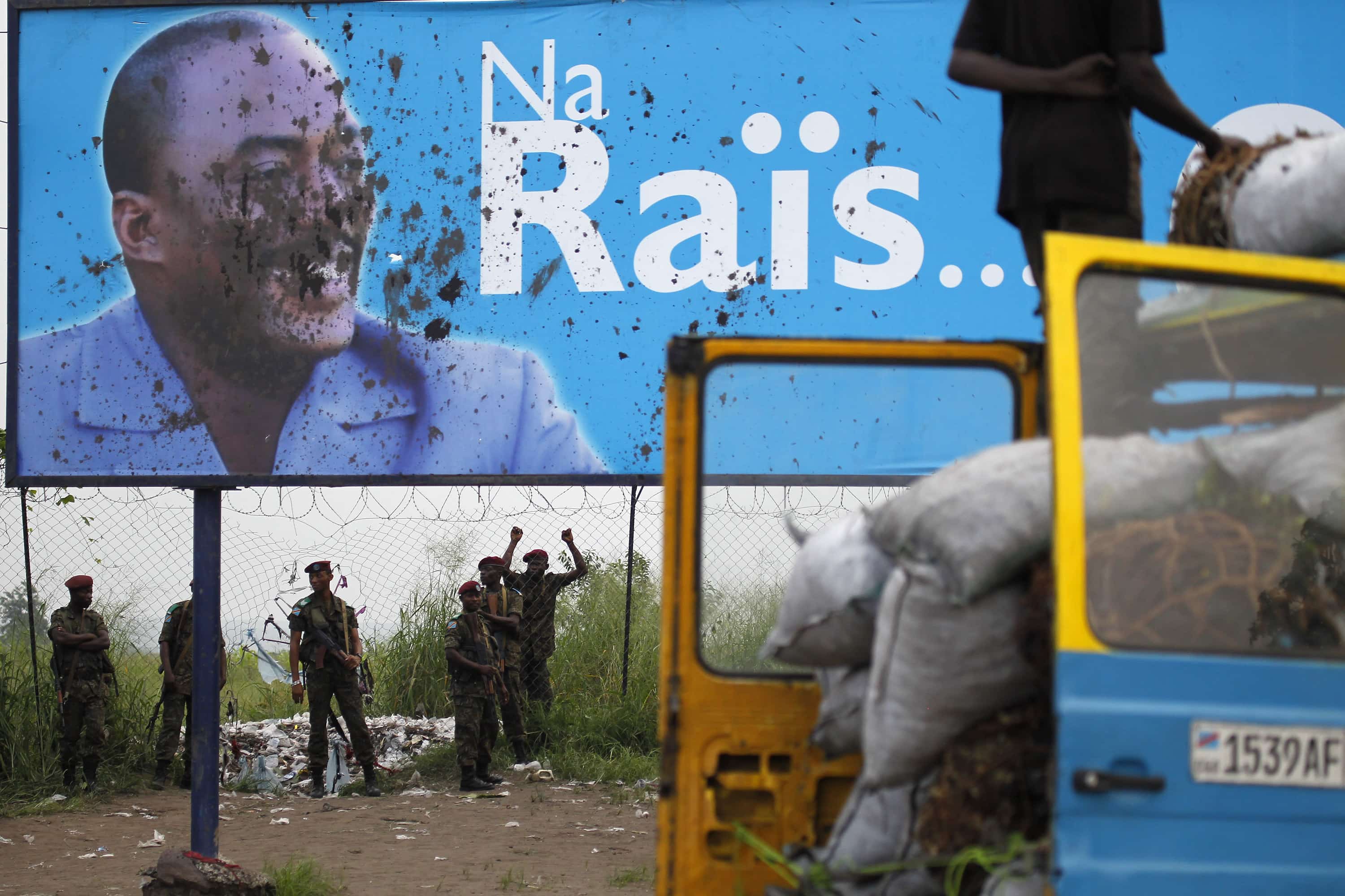 Presidential guardsmen stand under the stained campaign poster of Congolese President Joseph Kabila, 26 November 2011., AP Photo/Jerome Delay