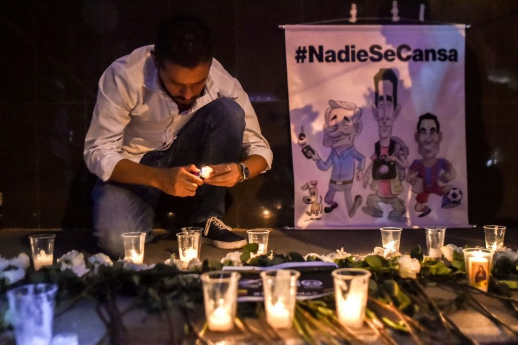 Un reportero gráfico enciende una vela durante el funeral de los periodistas de "El Comercio" en Cali, Colombia, el 26 de junio de 2018, LUIS ROBAYO/AFP/Getty Images