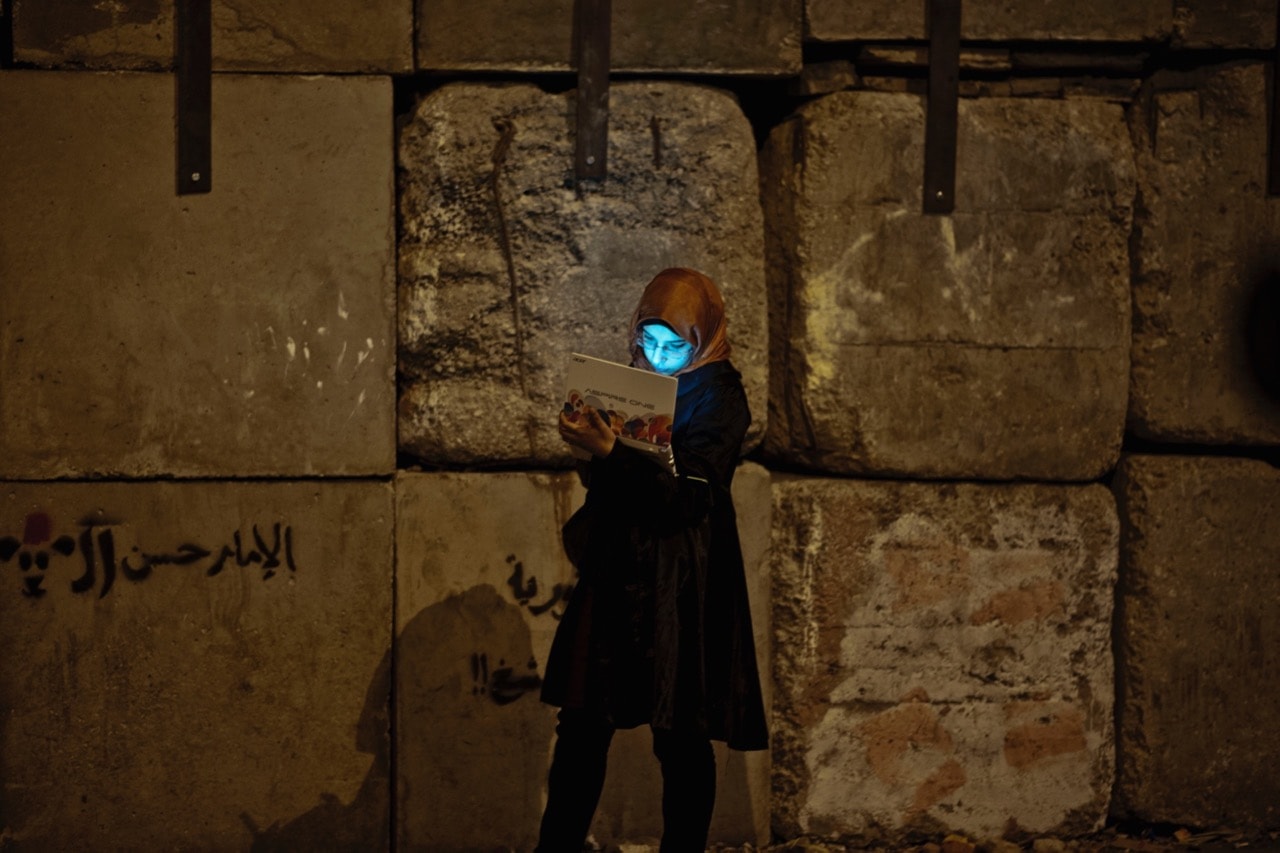 A young woman protesting against the Morsi government uses her laptop by the wall protecting the presidential palace, in Cairo, Egypt, 11 December 2012, Marco Vacca/contributor/Getty Images