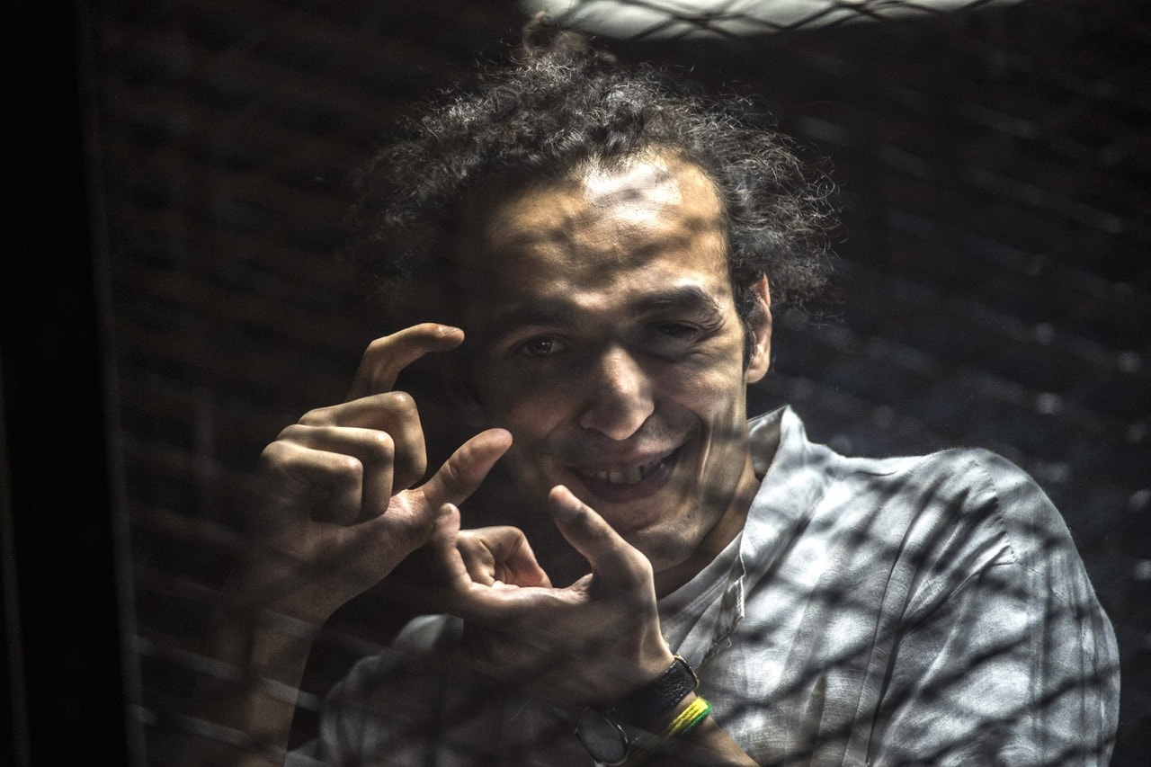 Egyptian photographer Shawkan gestures from inside a soundproof glass dock, during his trial in Cairo, 9 August 2016, KHALED DESOUKI/AFP/Getty Images