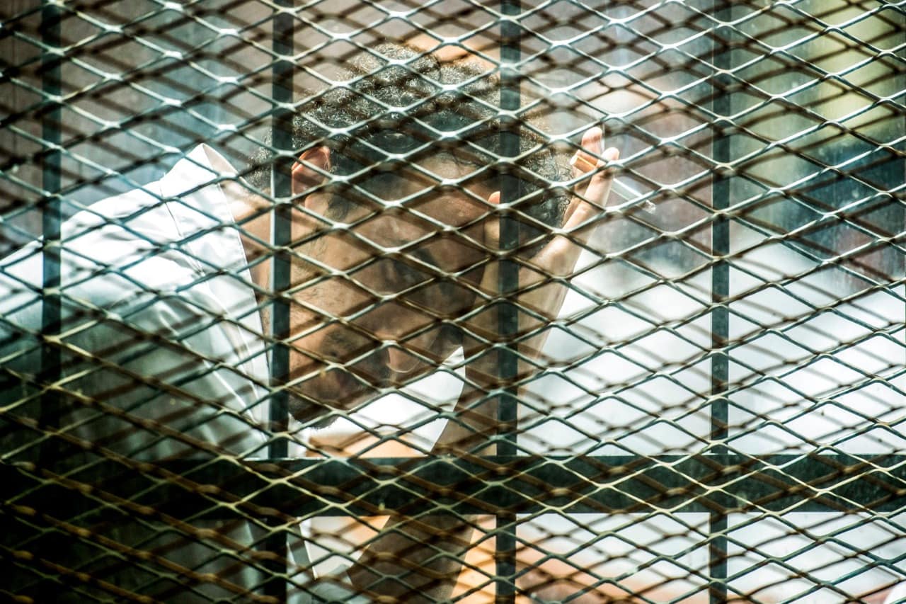 Egyptian photojournalist Mahmoud Abu Zeid, widely known as Shawkan, sits inside a soundproof glass dock during his trial in Cairo, 8 September 2018, MOHAMED EL-SHAHED/AFP/Getty Images