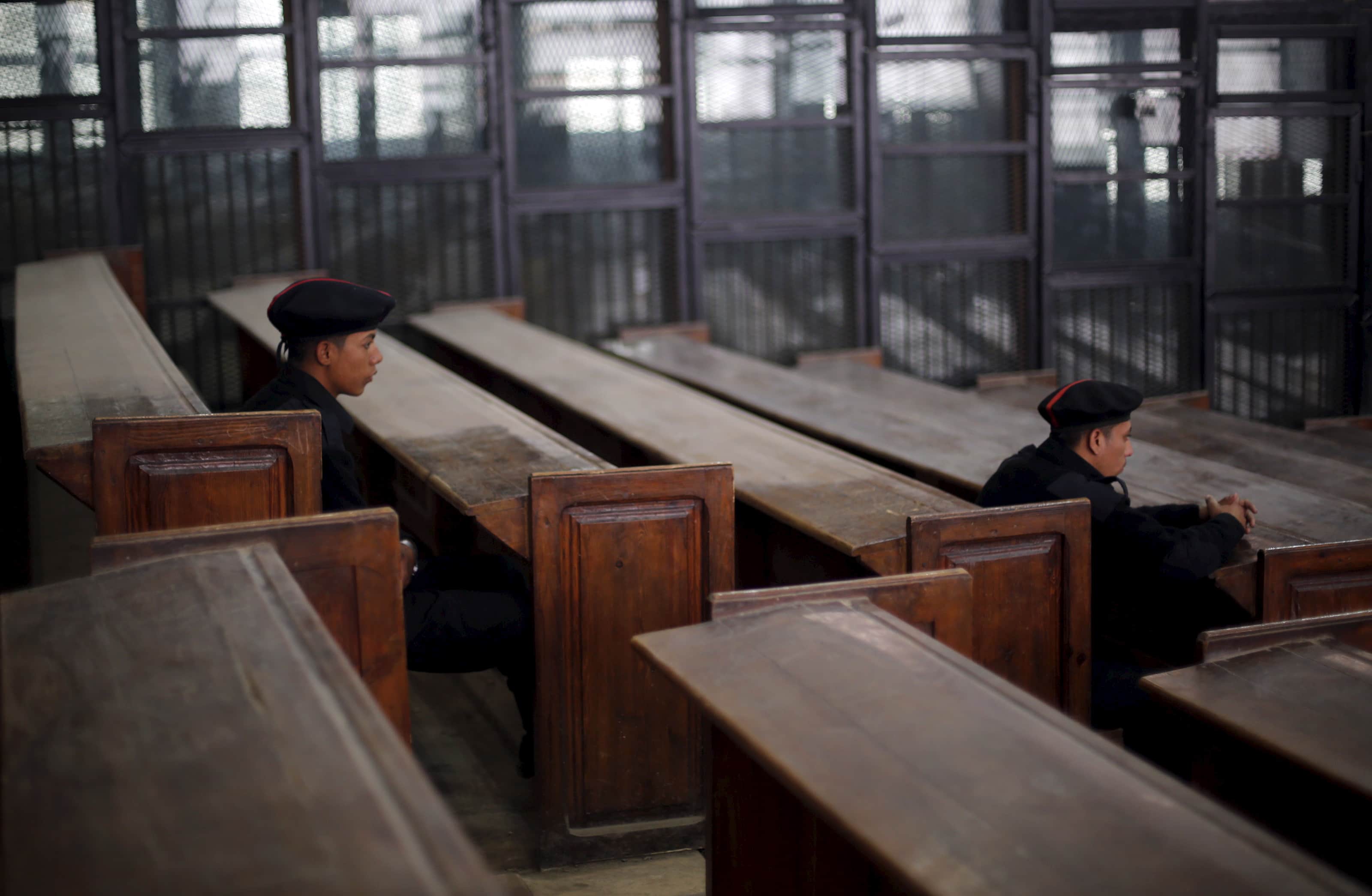 Policemen sit in front of empty bars during the verdict hearing in a case rooted in violence that swept Egypt after the military-led ouster of Mohammed Morsi (11 April 2015), REUTERS/Amr Abdallah Dalsh