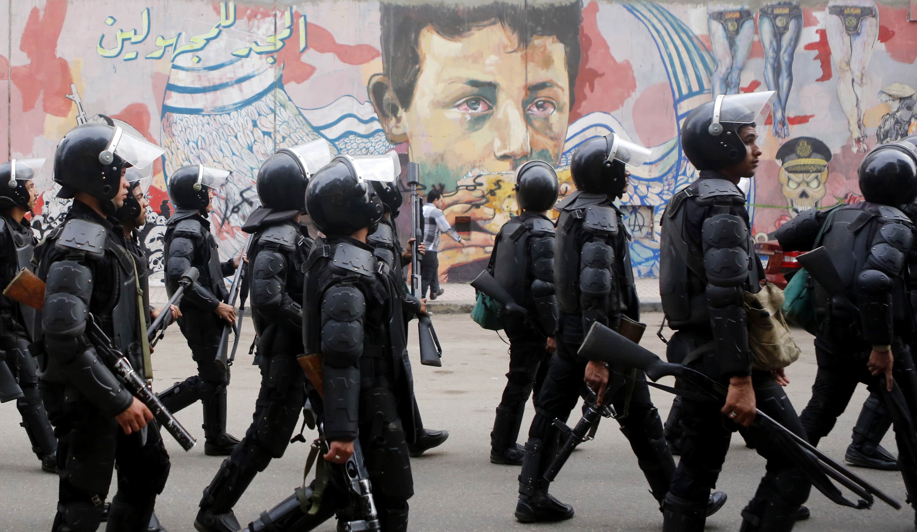 Riot police walk in front of graffiti representing Egypt's unrest during the third anniversary of deadly clashes near Tahrir Square in Cairo on 19 November 2014, REUTERS/Amr Abdallah Dalsh