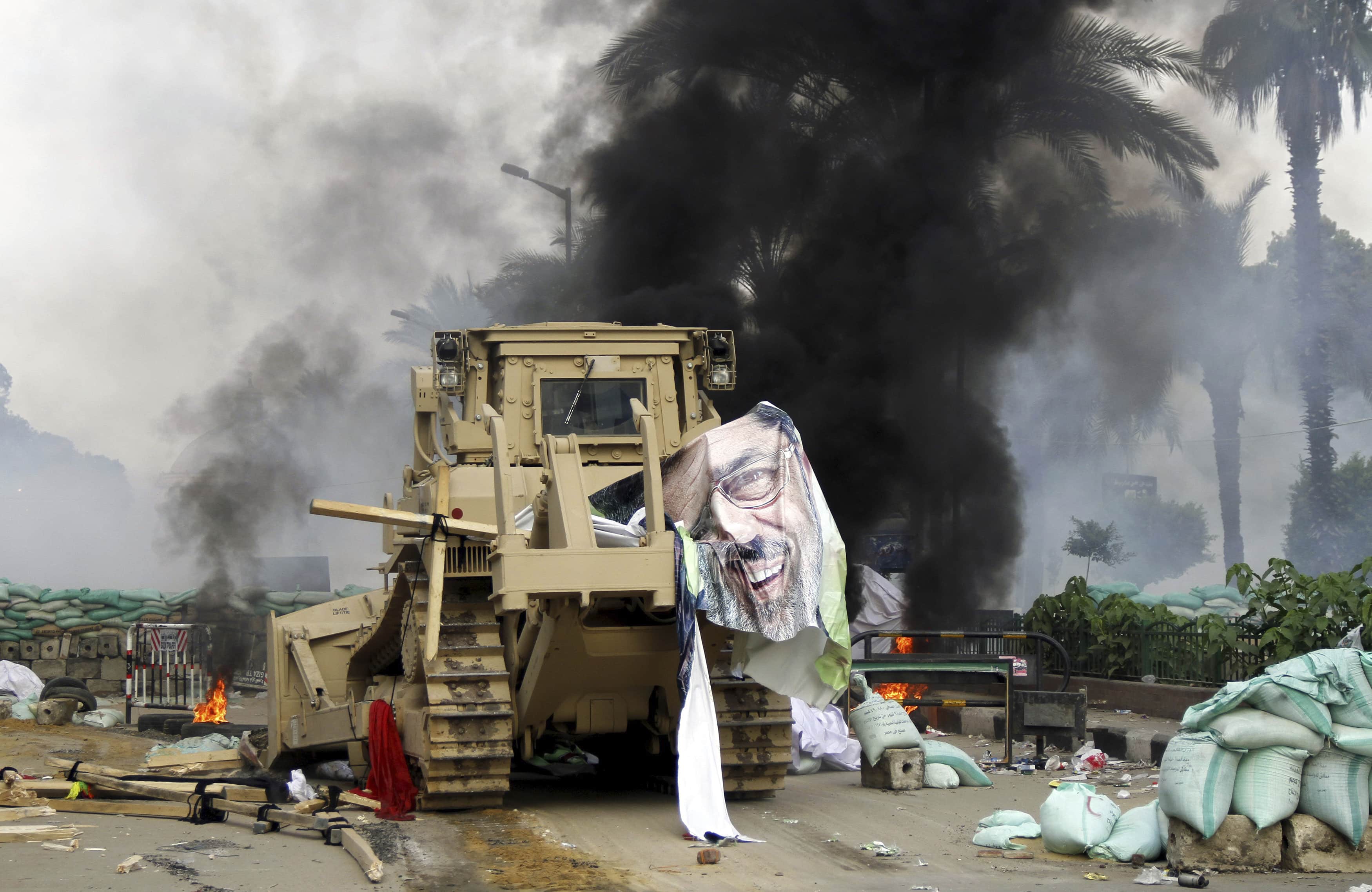 A poster of deposed president Mohamed Morsy which reads, "No to the coup", is pictured near debris of a protest camp outside the burnt Rabaa Adawiya mosque, in Cairo on 15 August 2013, REUTERS/Mohamed Abd El Ghany