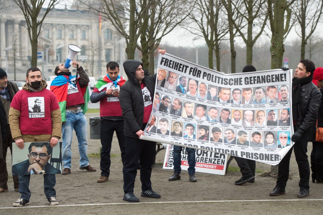 Protesters carry a banner with the portraits of Azerbaijani political prisoners during a demonstration for press freedom, in Berlin, Germany, 21 January 2015, Maurizio Gambarini/picture alliance via Getty Images