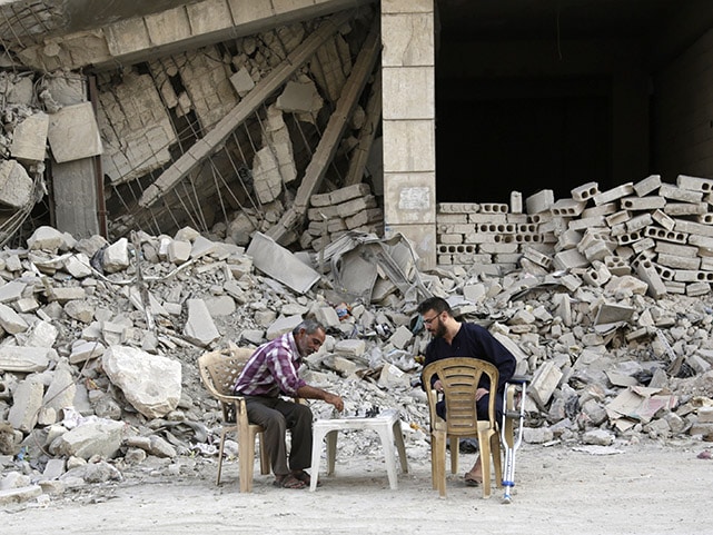 Men play chess in front of a damaged building in the rebel-controlled area of Maaret al-Naaman town in Idlib province, Syria October 19, 2015, REUTERS/Khalil Ashawi