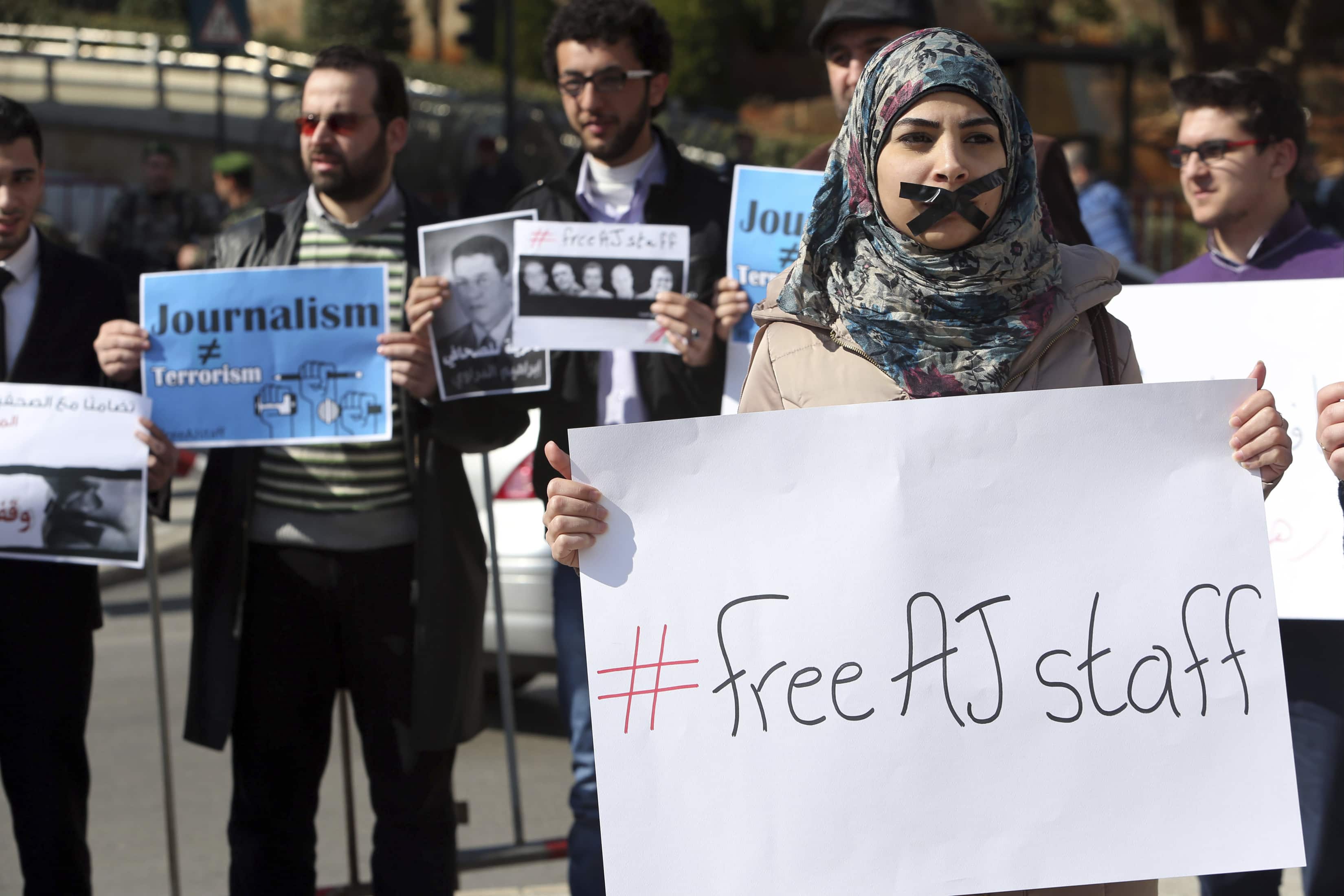 A protester, with a taped mouth, stands with a sign during a protest against the detainment of Al Jazeera journalists in Egypt, in Lebanon on 8 February 2014, REUTERS/Hasan Shaaban