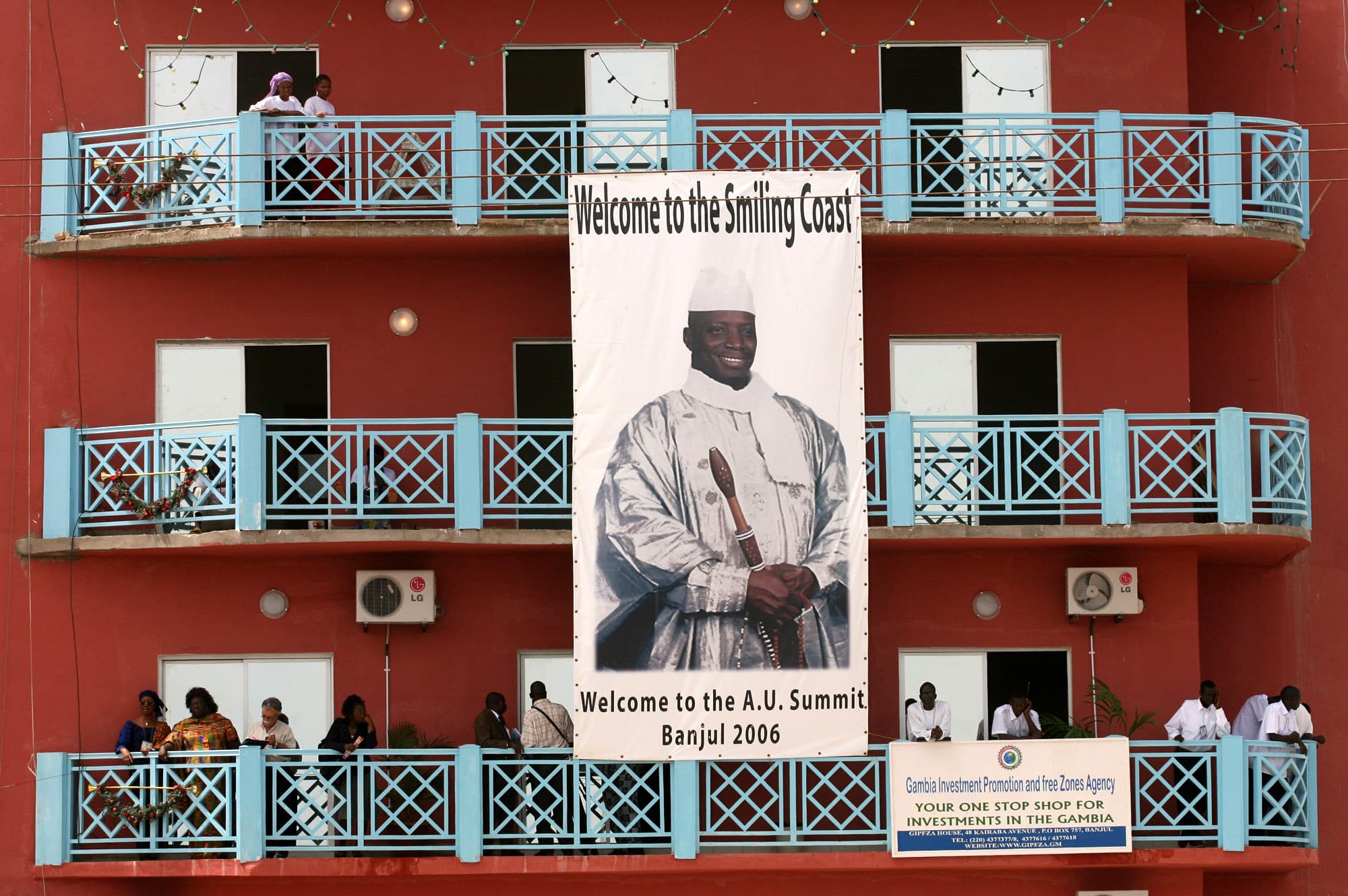 People stand near a large picture of the Gambian President Yahya Jammeh at the media centre building in Banjul, 1 July 2006. , AP Photo/ George Osodi