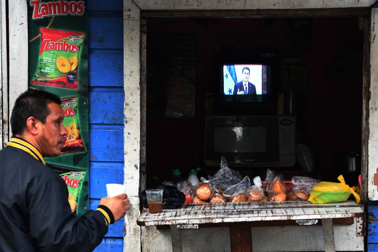 A man drinks fruit juice while President Juan Orlando Hernández gives a message on TV in Tegucigalpa, Honduras, 19 December 2017, ORLANDO SIERRA/AFP/Getty Images