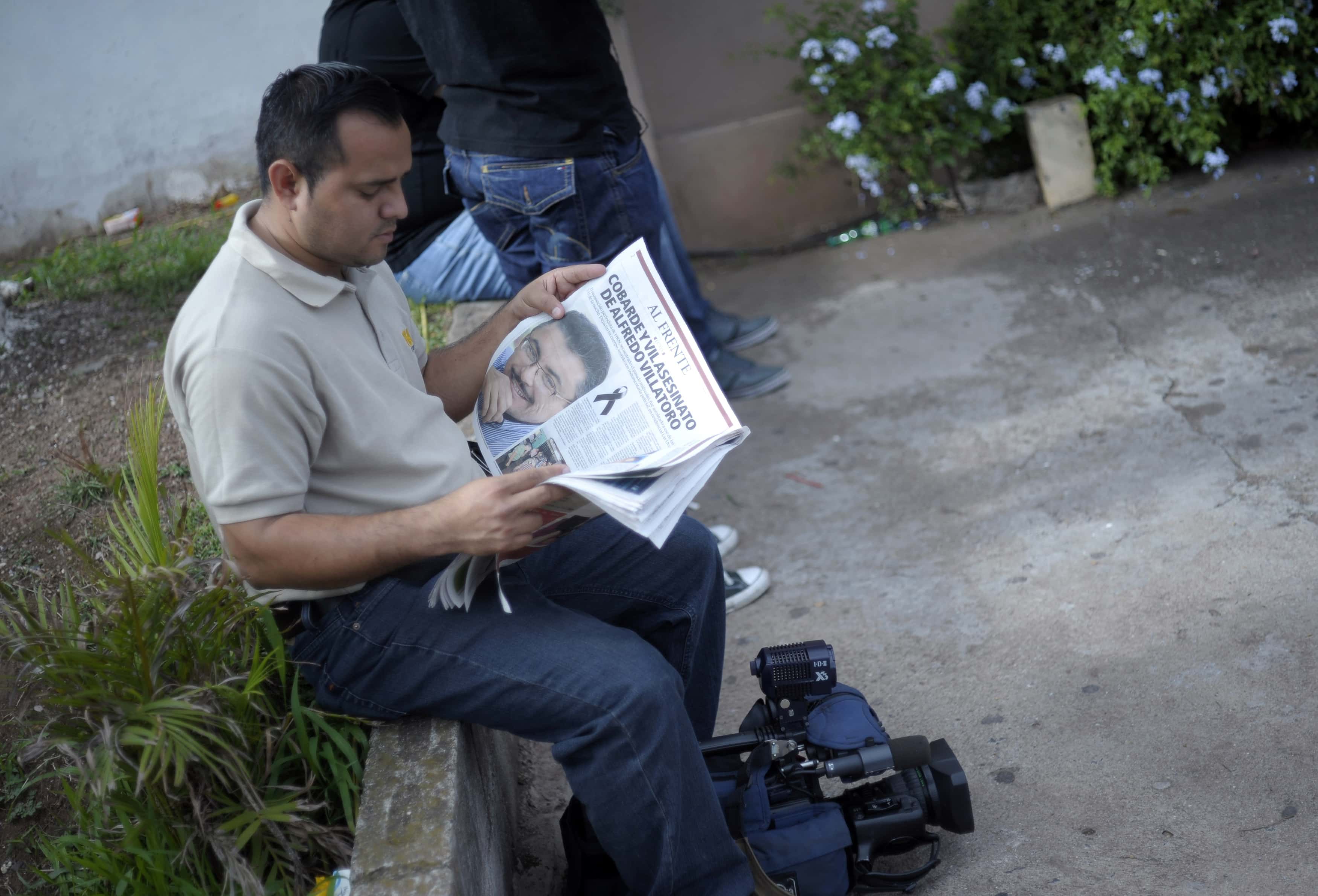 A journalist reads a local paper with a photograph of fellow journalist Alfredo Villatoro outside a funeral home where a wake for Villatoro was taking place in Tegucigalpa 16 May 2012, REUTERS/Jorge Cabrera