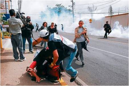 C-Libre member Cesar Villeda assisting his colleague Tirzia Gáleas, who is suffering from the after-effects of tear-gas inhalation, C-Libre