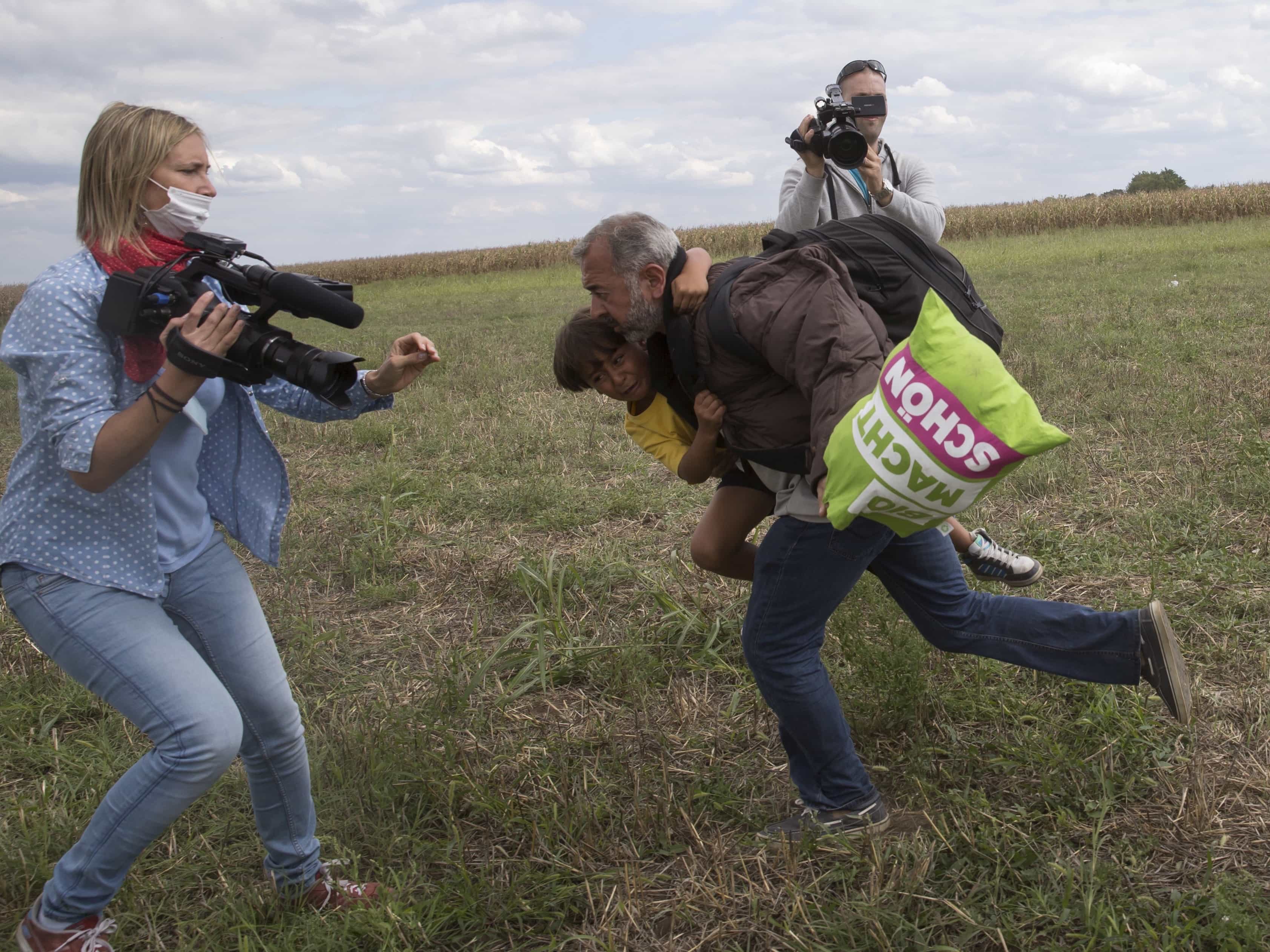 A migrant runs with a child before being tripped by TV camerawoman Petra Laszlo (L) and falling as he tries to escape from a collection point in Roszke village, Hungary, 8 September 2015. , REUTERS/Marko Djurica