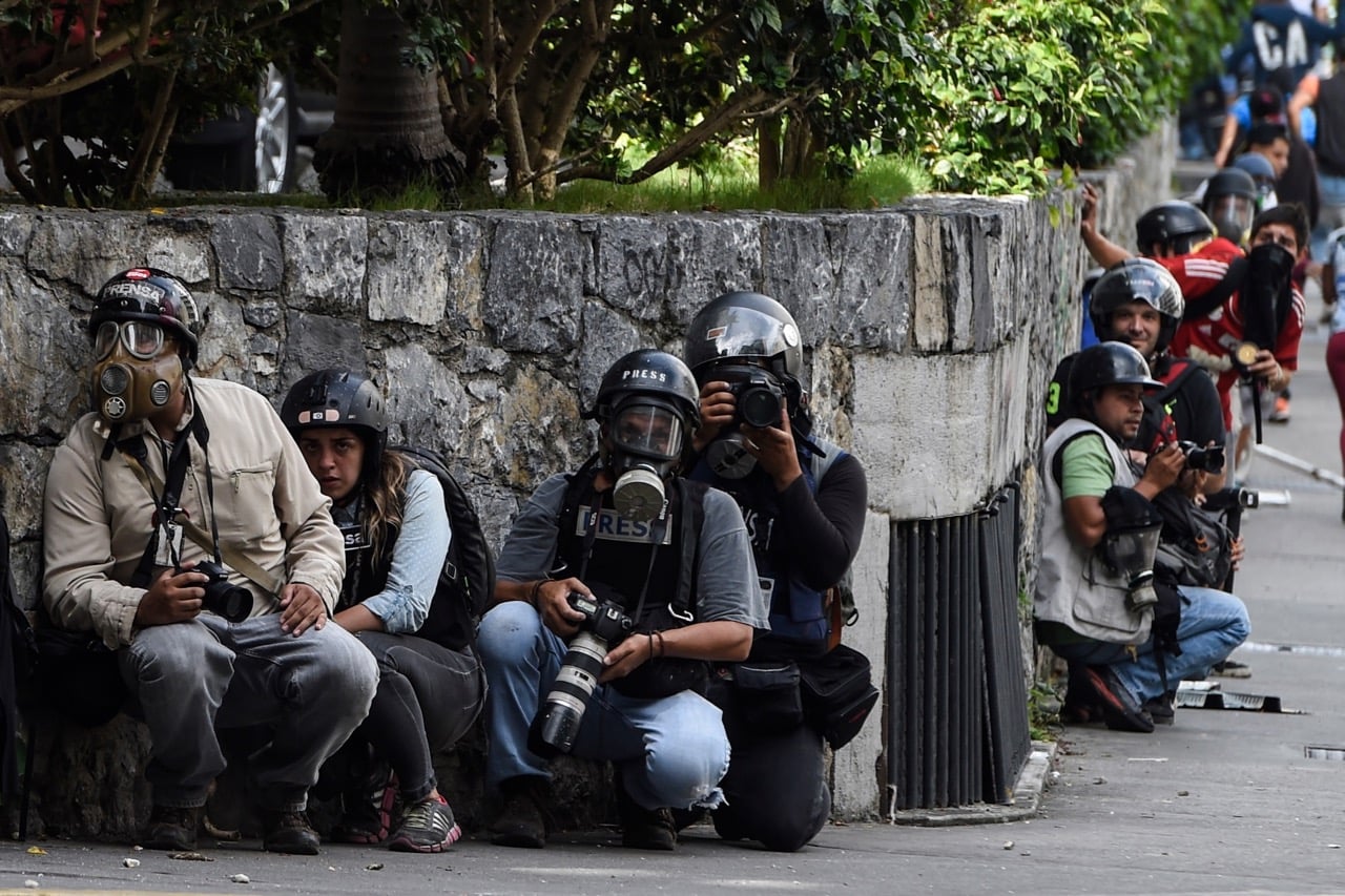 Journalists take shelter during clashes between anti-government protesters and riot police in Caracas, Venezuela, 14 June 2017, JUAN BARRETO/AFP/Getty Images