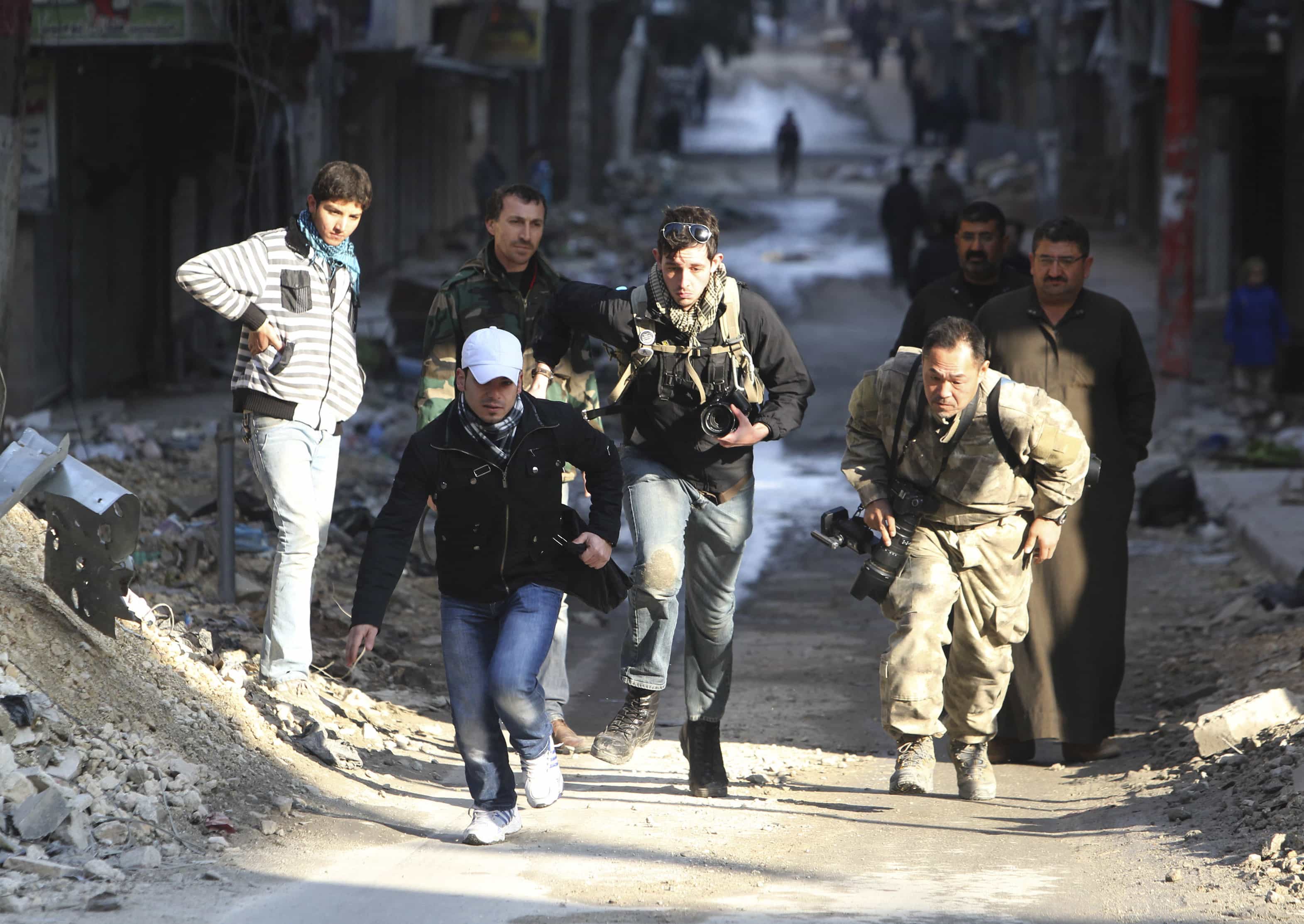 In this December 2012 photo, journalists Bryn Karcha (C) of Canada and Toshifumi Fujimoto (R) of Japan run for cover next to an unidentified fixer in a street in Syria, REUTERS/Muzaffar Salman