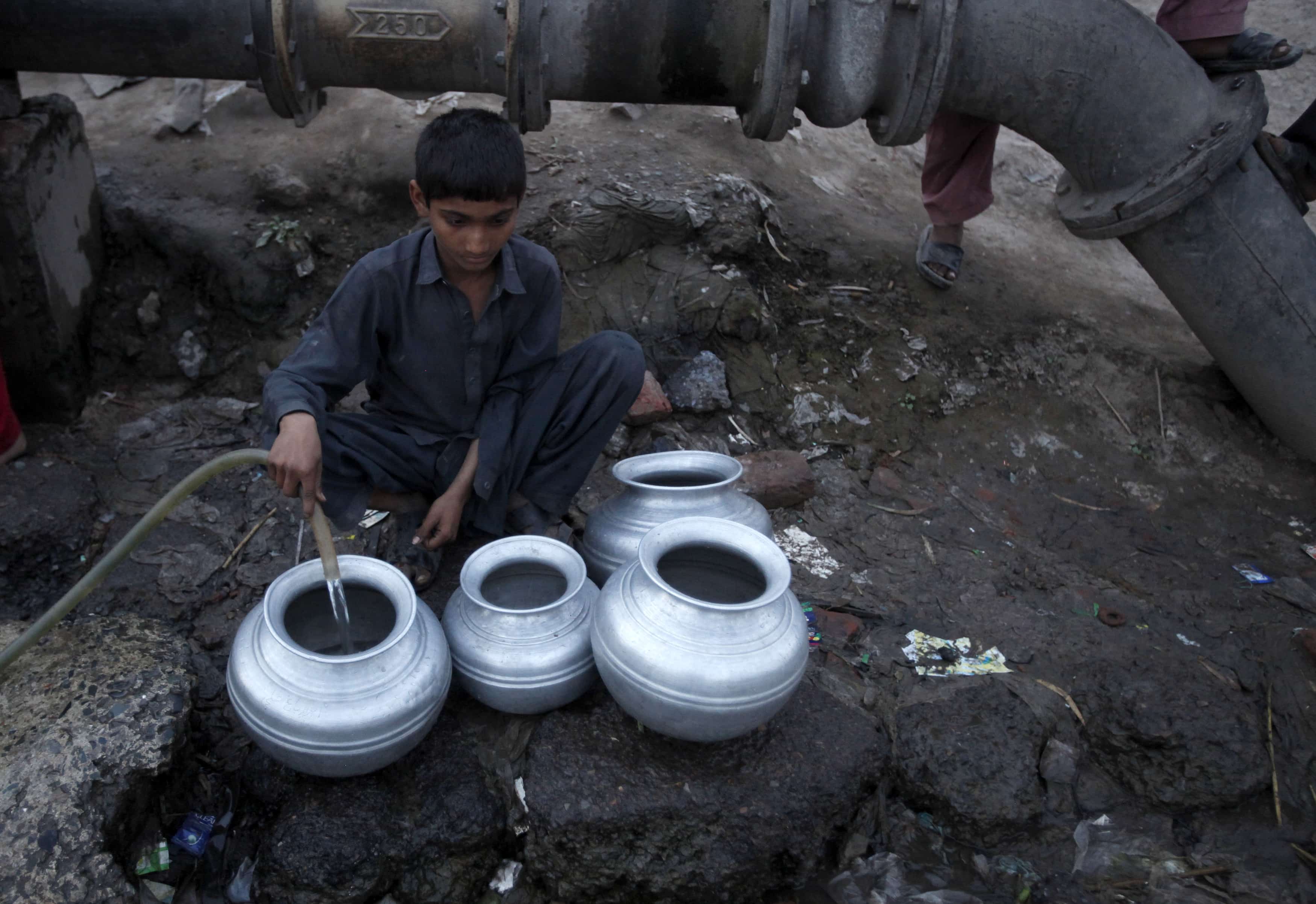A boy collects drinking water for his family in a slum on the outskirts of Lahore, 21 March 2014. World Water Day will be marked on 22 March, REUTERS/Mohsin Raza