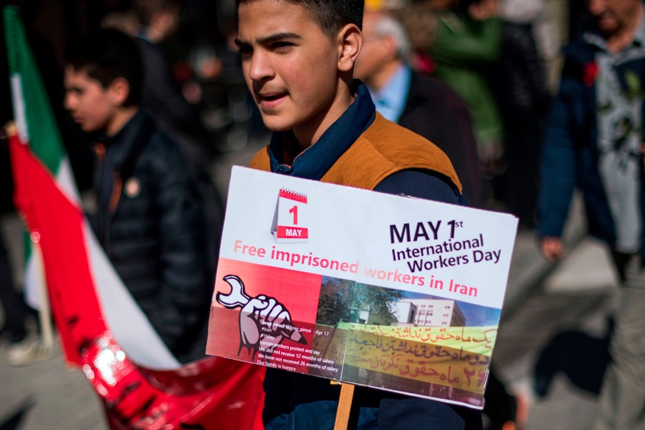 A protester holds a sign reading 'Free imprisoned workers in Iran' as he takes part in a May Day (Labour Day) rally in Stockholm, Sweden, 1 May 2018, JONATHAN NACKSTRAND/AFP/Getty Images