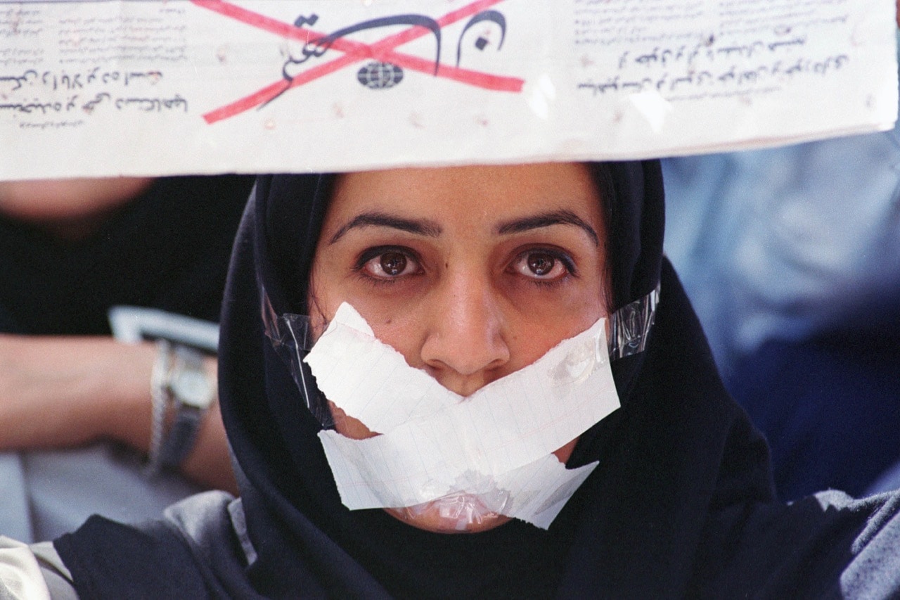 A female student demonstrates against censorship at Tehran university, after reformist newspapers were closed down, 22 May 2000; she holds a copy of the newspaper 'Kayhan', known for its extremist pro-regime ideas, upside down, Kaveh Kazemi/Getty Images